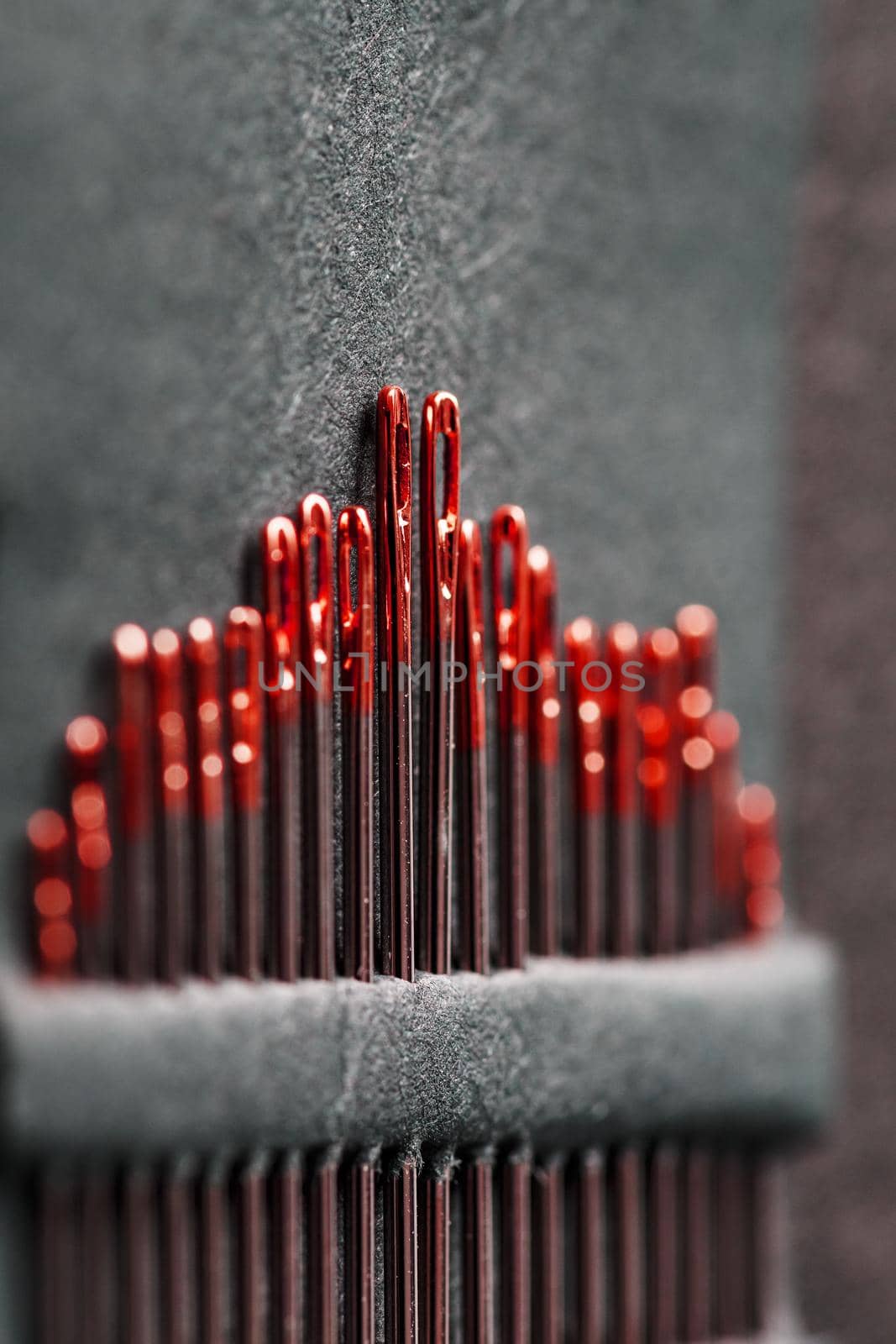 Sewing needles of different sizes in a set of red on a black background. Macro