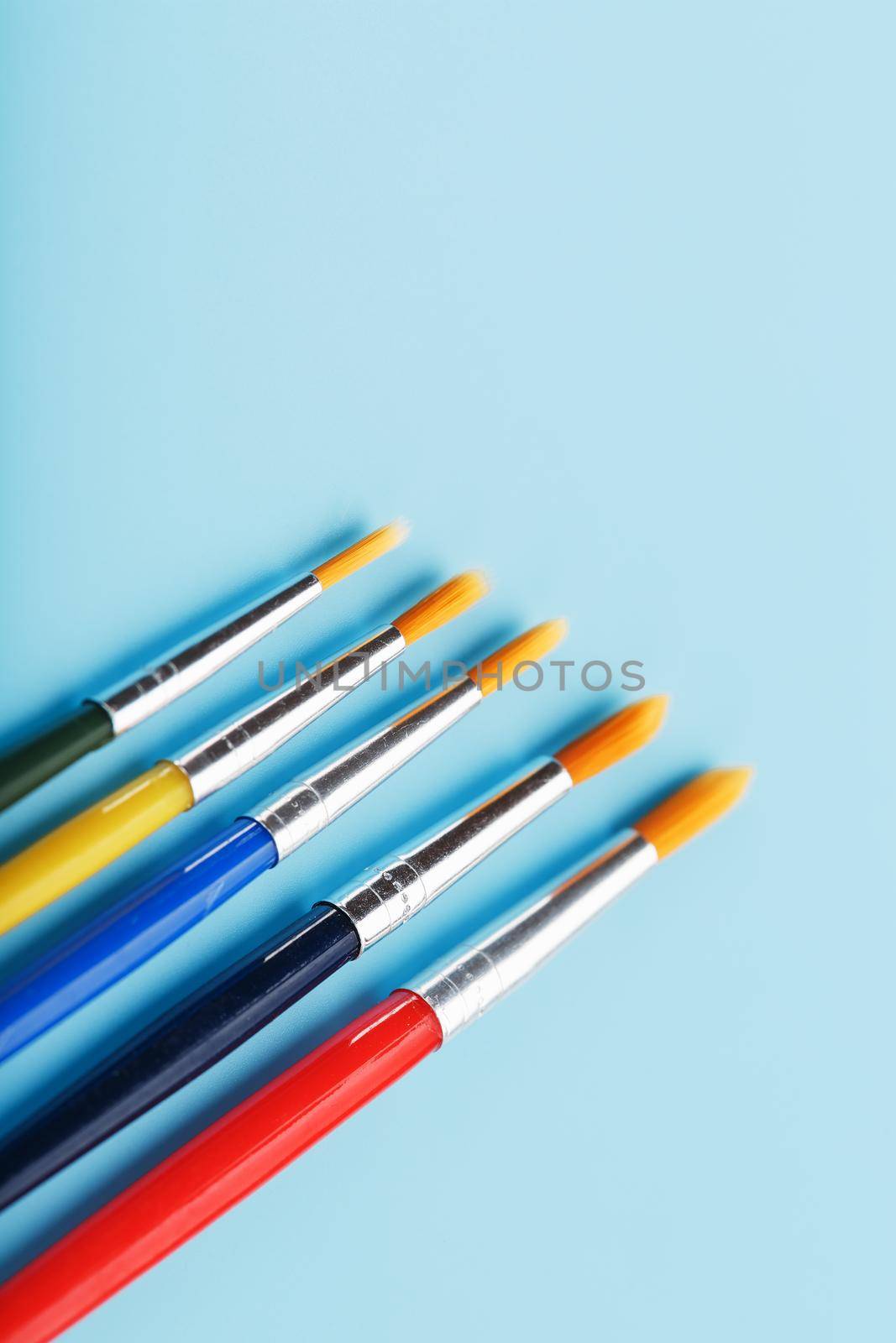 Multi-colored paint Brushes on a blue background. Free space