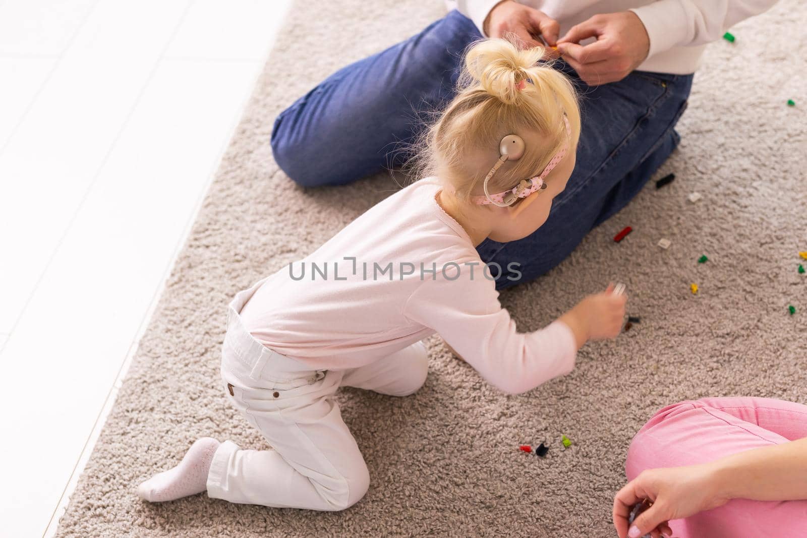 Kid with cochlear implants playing with toys at home. Deafness and medical technology