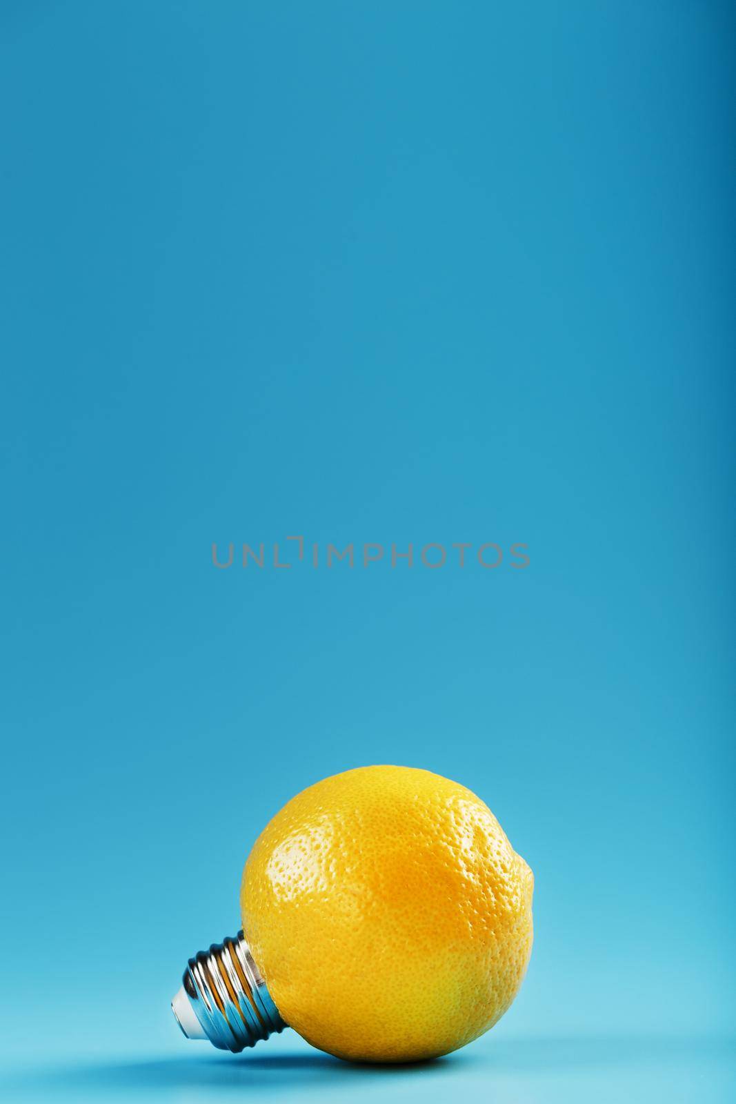 The light bulb is like a lemon on a blue background. Lemon fruit with a light bulb cartridge. Concept of an idea