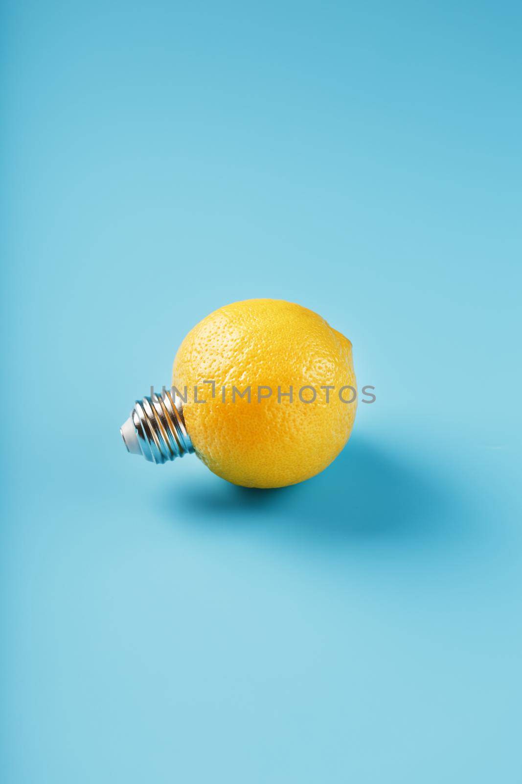 The light bulb is like a lemon on a blue background. Lemon fruit with a light bulb cartridge. Concept of an idea