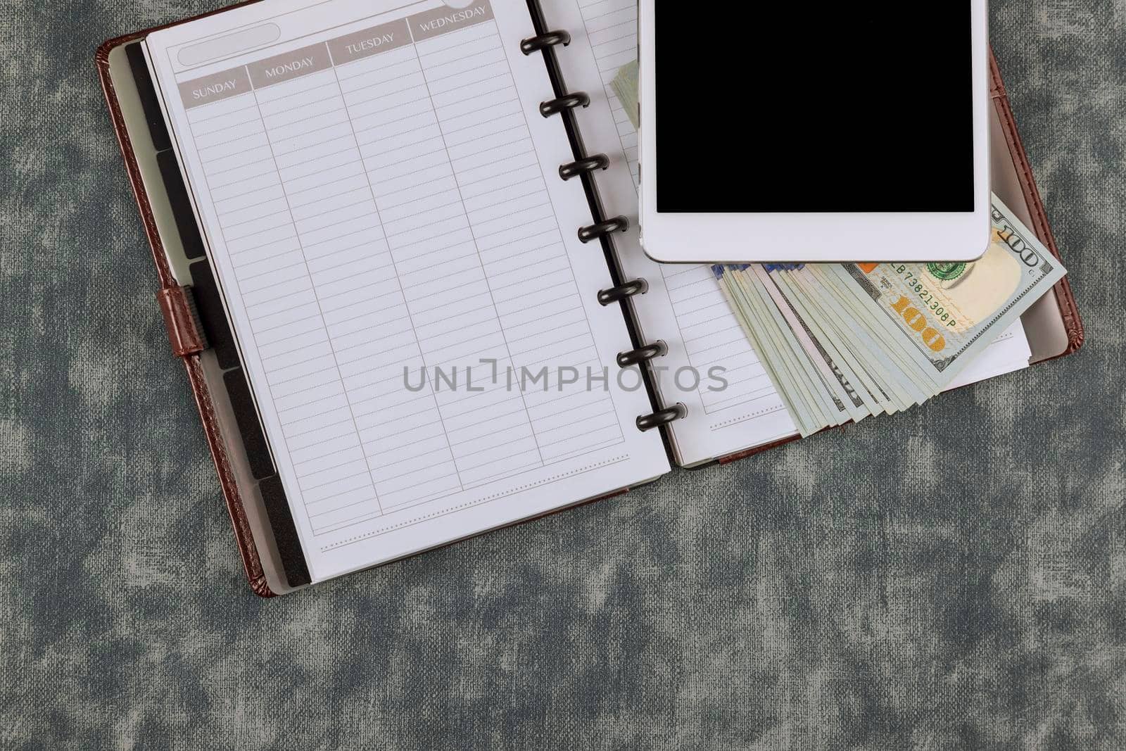 Office workplace table with blank paper notebook diary and one hundred dollars US the tablet digital devices by ungvar