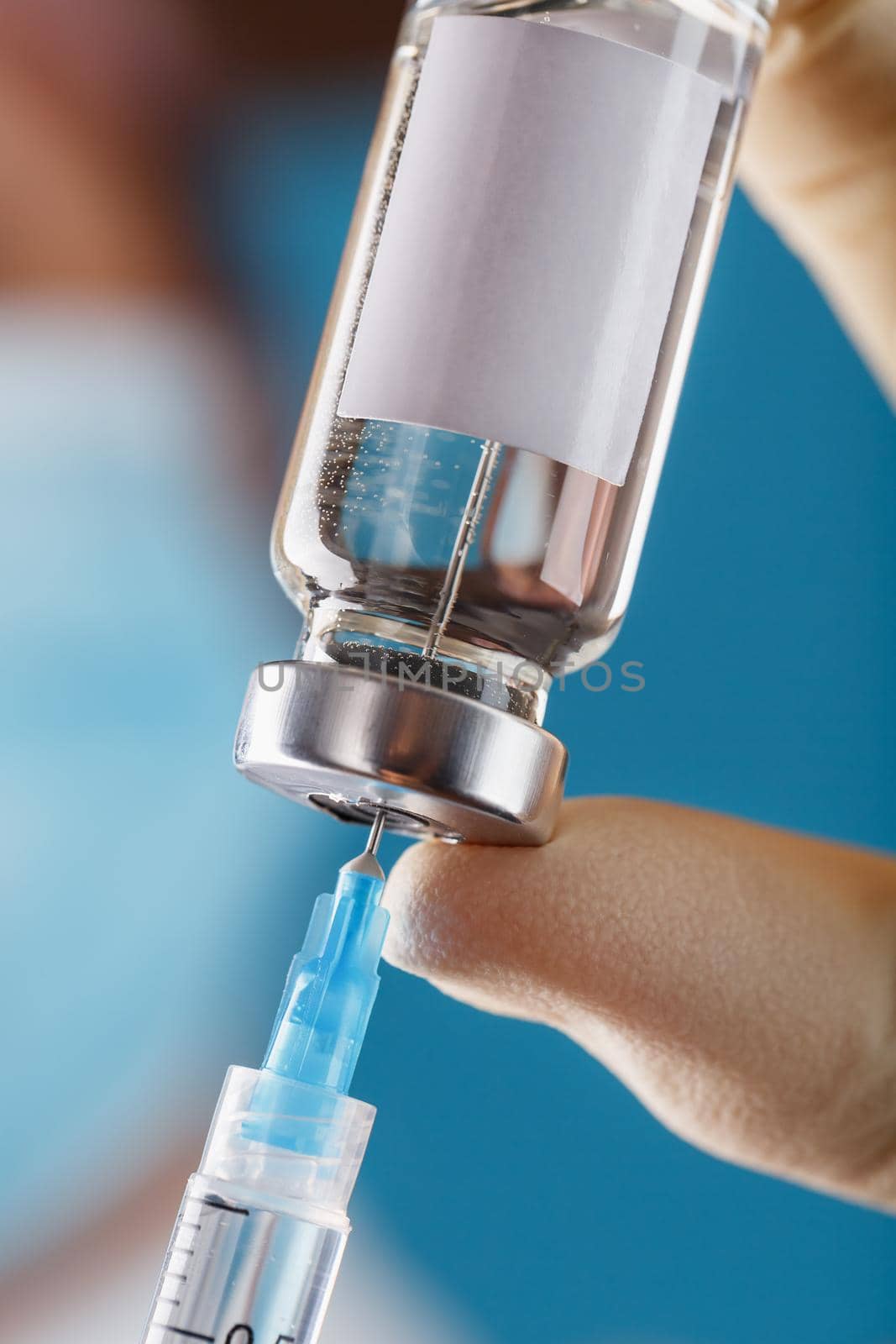 A doctor in rubber gloves holds an ampoule with a vaccine and a syringe, close-up. Free space for text on the sticker to the vial. Medicine for flu, measles, coronavirus, covid-19 vaccine disease, vertical frame