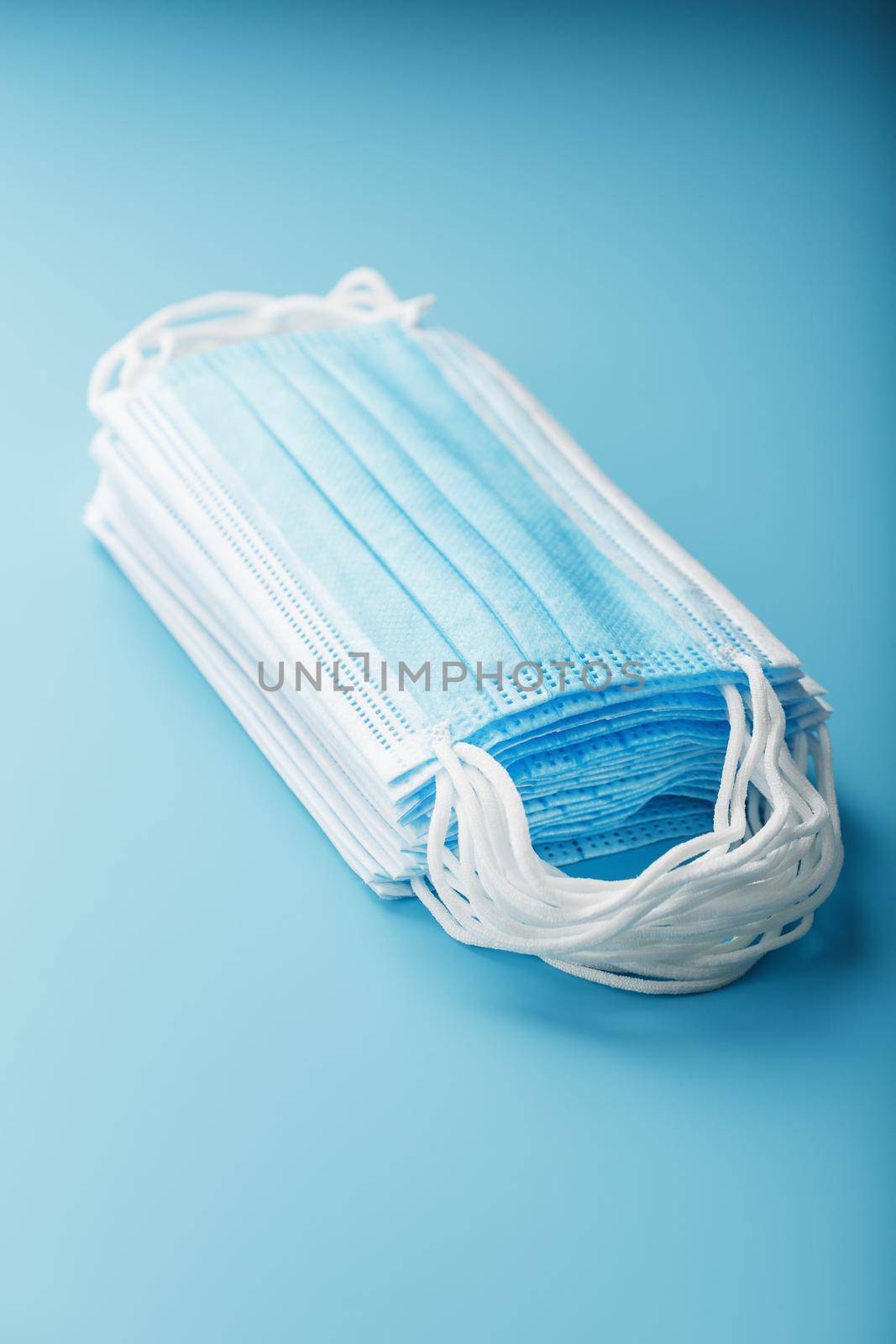 Medical protective masks on a blue background are stacked. Protection against disease, coronavirus, Covid-19, bacteria, pollution, influenza virus.