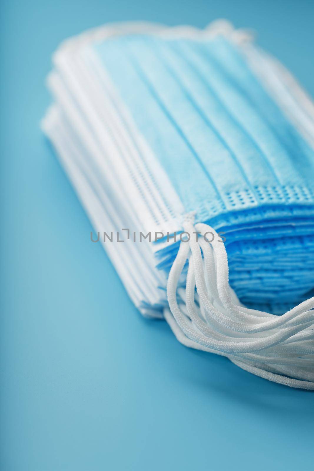 Stack of protective medical masks on a blue background, isolate. Protection against diseases viruses and bacteria, coronavirus, Covid-19, bacteria, pollution, influenza virus.