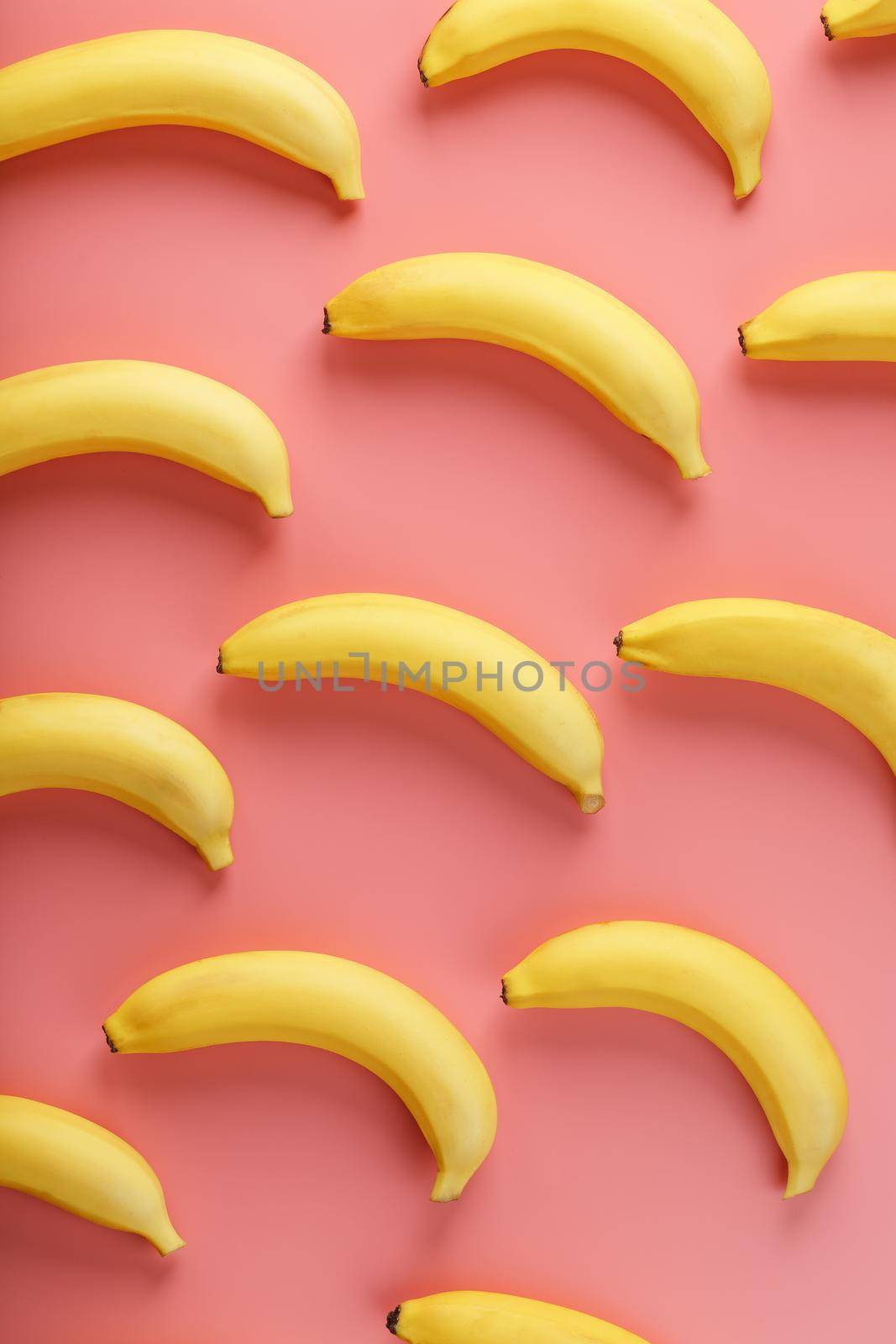 Bright pattern of yellow bananas on a pink background. View from above. Flat lay. Fruit patterns