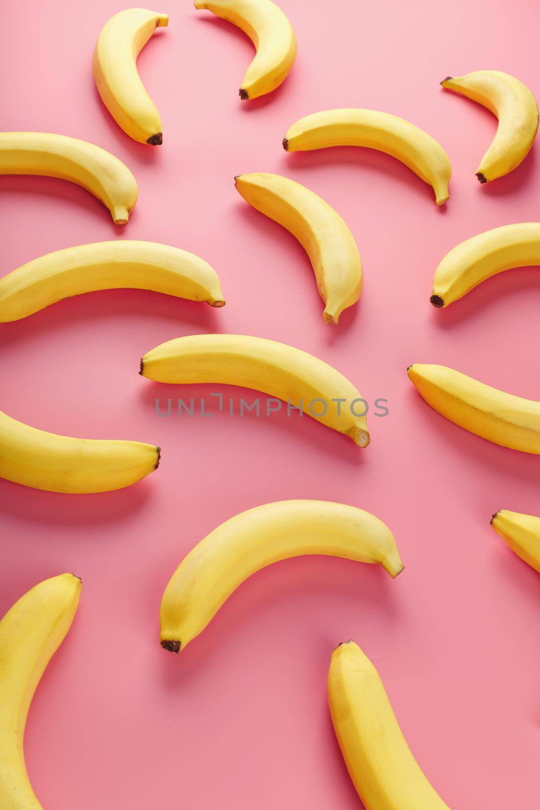 Bright pattern of yellow bananas on a pink background. View from above. Flat lay. Fruit patterns