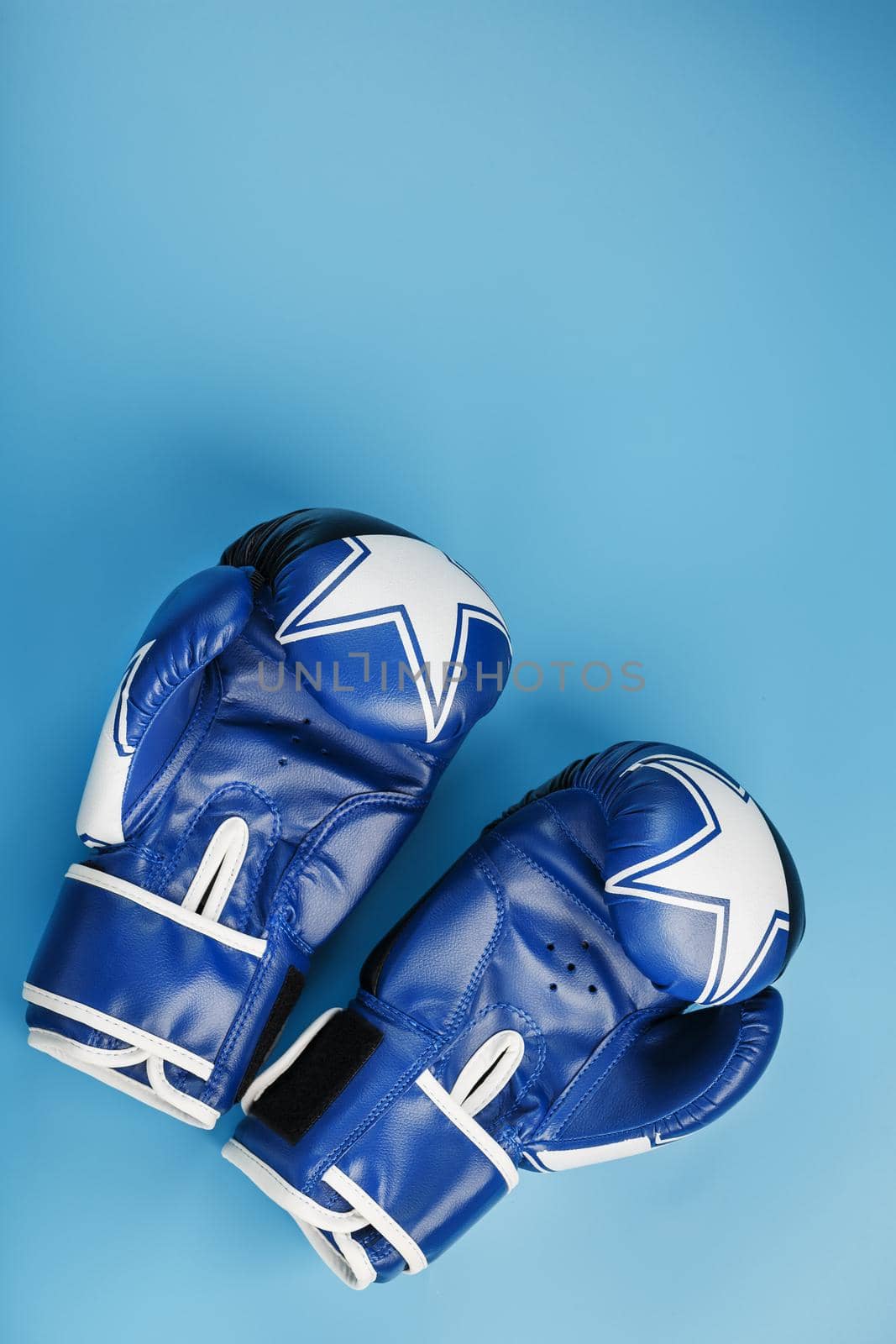 A pair of leather Boxing gloves on a blue background, free space. The concept of fighting and fighting with difficulties.