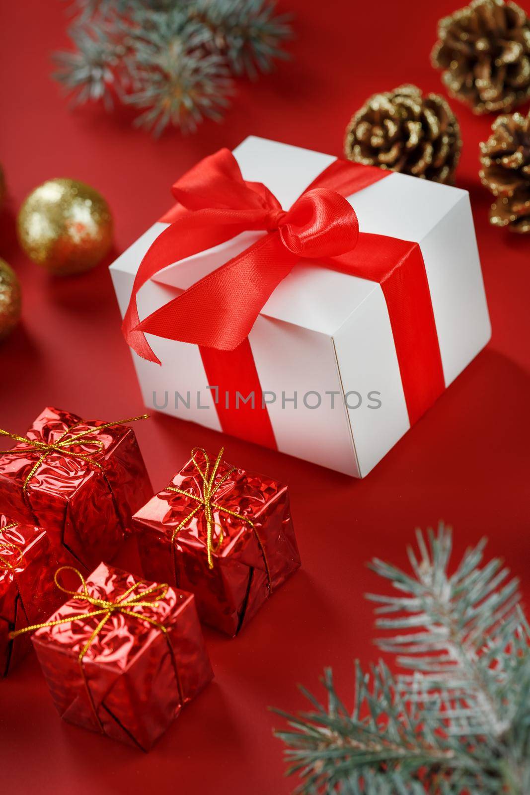 Christmas gift in the form of a white box with a red bow around Christmas decorations. New year's composition of the holiday.