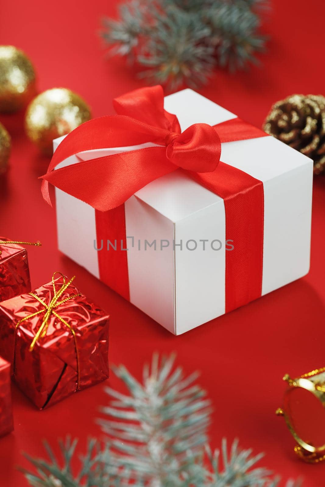 Box with a red bow around Christmas decorations on a red background. Close-up
