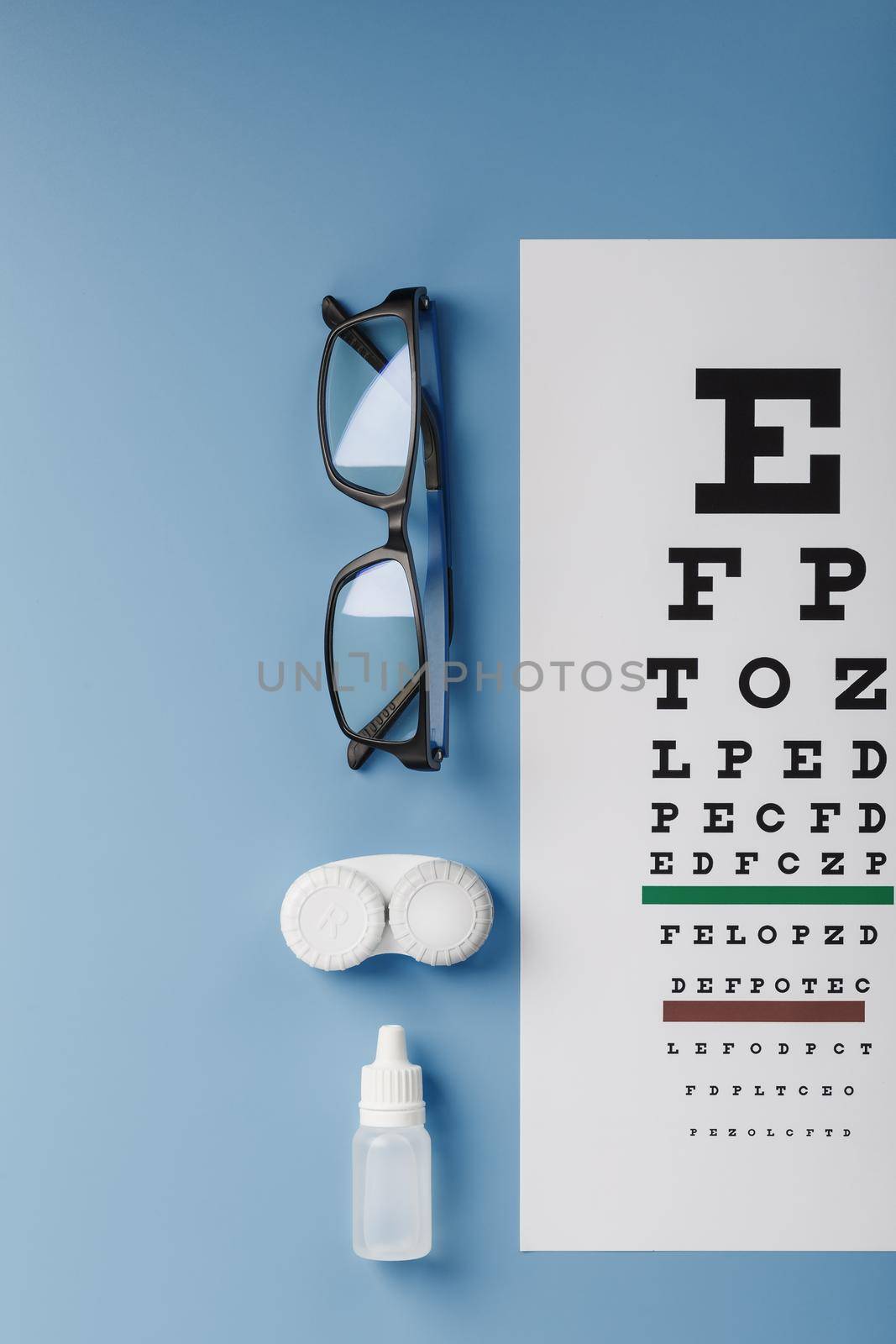 Ophthalmic Accessories Glasses and lenses with an Eye Test Chart for vision correction on a blue background. Treating vision problems. Close-up