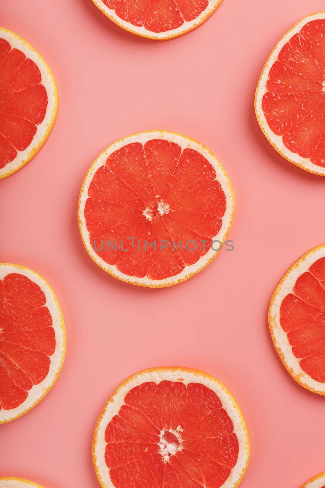 Patterns of slices of juicy grapefruit on a pink background, a beautiful pattern. Top view, full screen