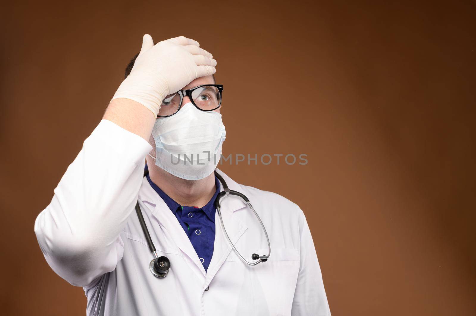 Male Caucasian doctor in white medical uniform shows face palm gesture. Chagrin and disappointment. Copy space.