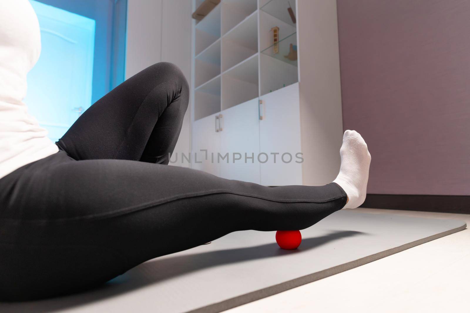 Close-up of self-massage of a sports woman indoors using a massage ball. Myofascial massage without a masseur. Elimination of pain in leg muscles by yanik88
