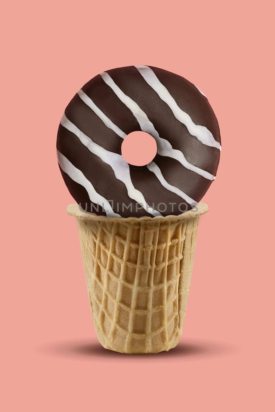 Delicious chocolate donut with white icing in sweet wafer cup against pink background. Concept of food, treats and unhealthy nutrition. Close up, copy space