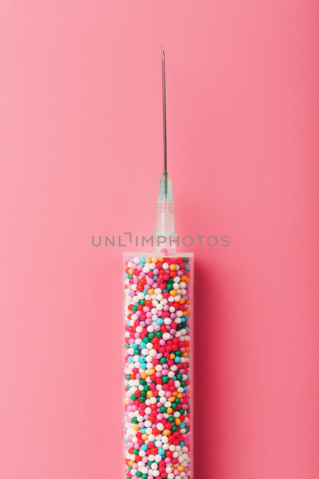 Medical Syringe filled with colorful balloons on a pink background with free space. Conceptual medical vaccine development.