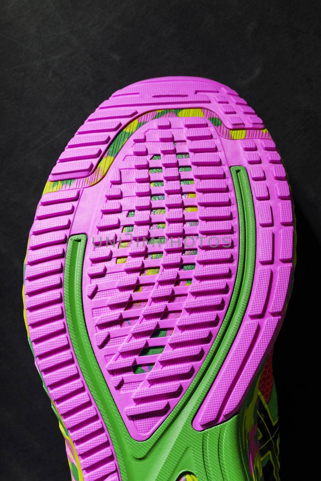Textured pink sole of sports running shoes on a black background. Crazy modern colors. Sporty style, close-up