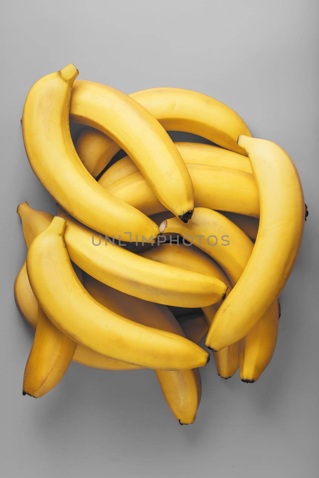 A bunch of fresh yellow bananas on a gray background in the fashionable colors of 2021. Top View. Minimalistic concept. Free space.