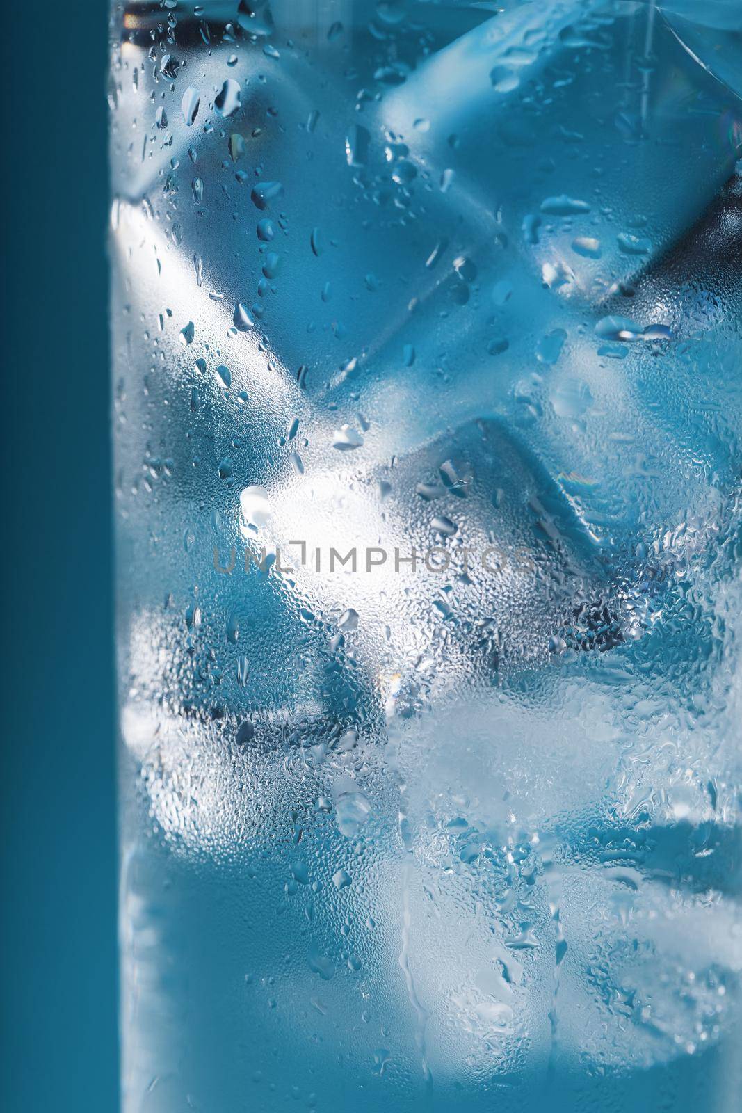 A glass with ice water and ice cubes on a blue background. by AlexGrec