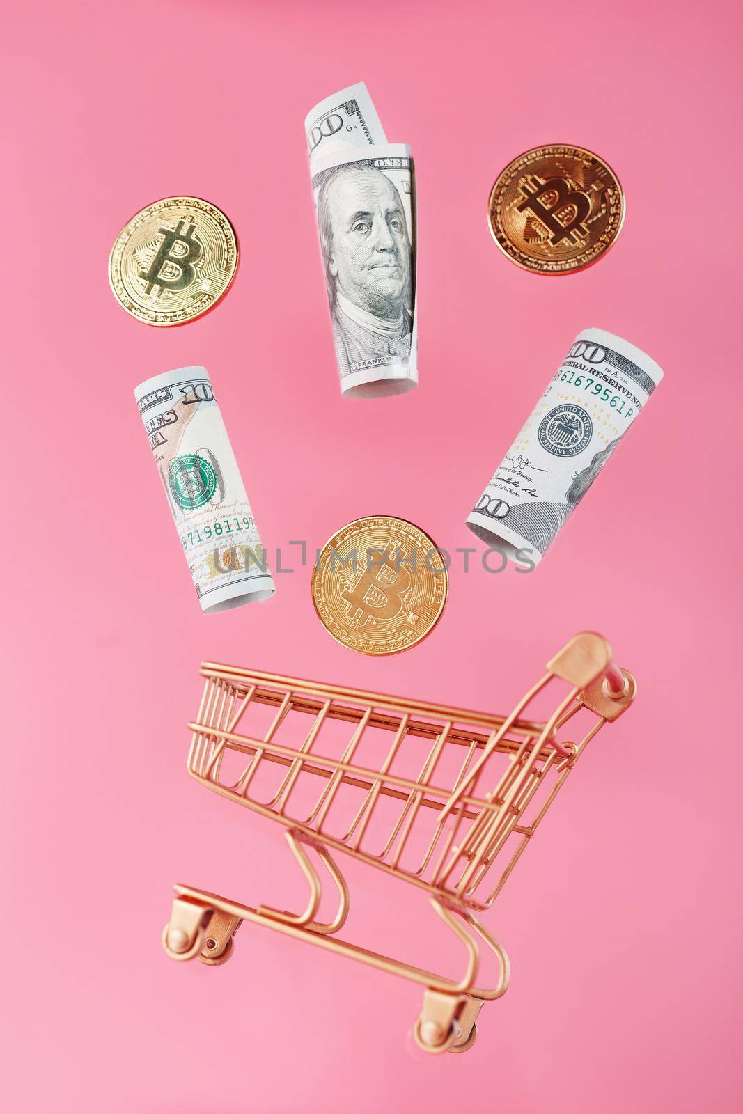 Gold mini cart with bitcoin coins and US dollars in a flight of levitation on a pink background. by AlexGrec