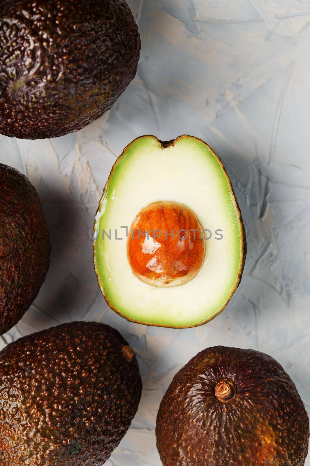 Sliced and whole organic Hass avocado on a gray background. A source of essential fats, vitamins, trace elements, beta-carotene and omega-3 fatty acids. Healthy food, diet. copy space