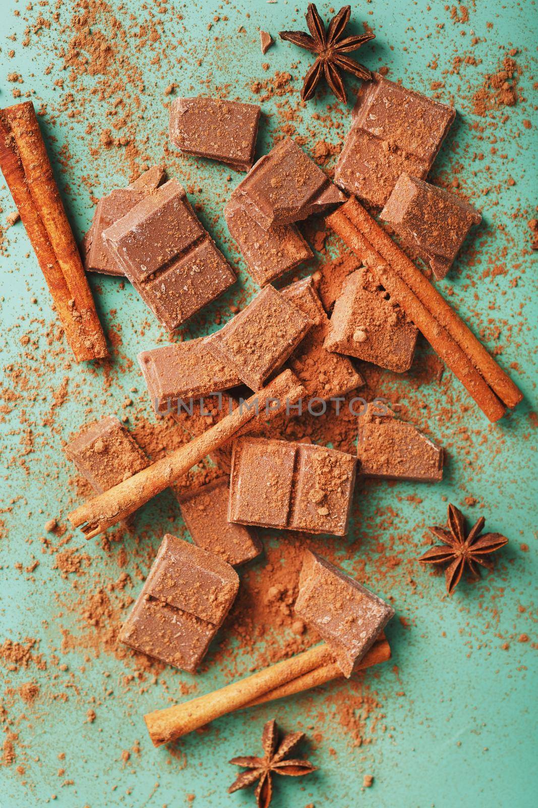 Milk chocolate with spices and cocoa on a green background. Delicious and healthy dessert. Free space, top view Close-up