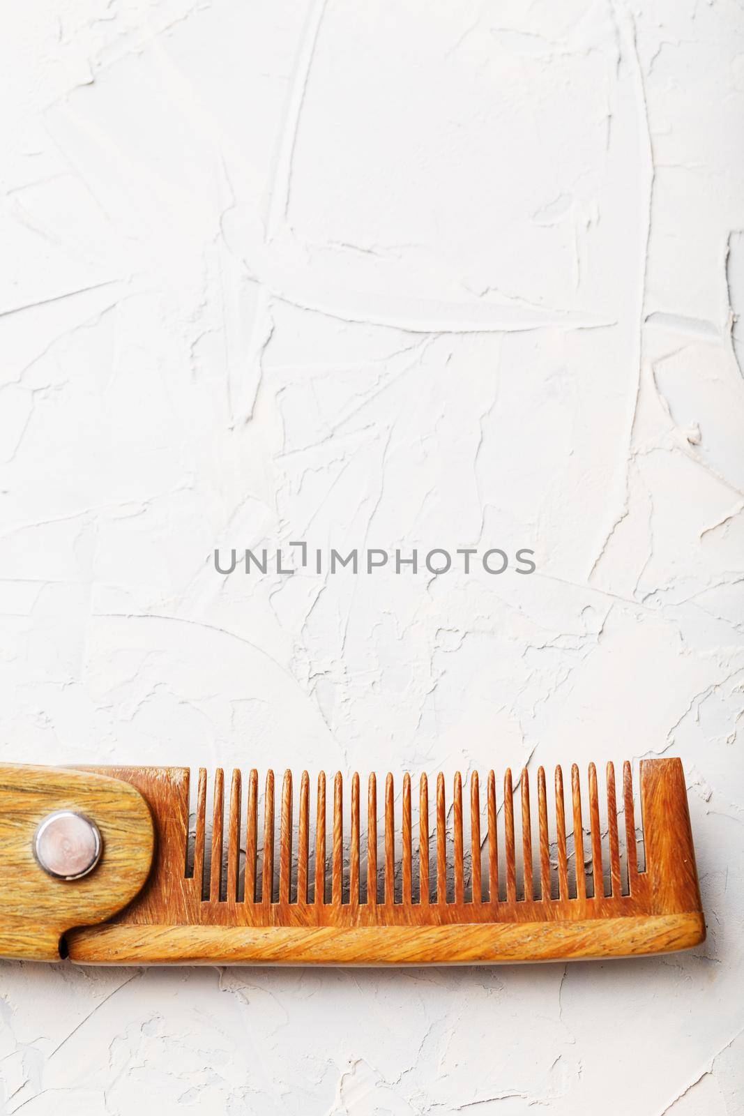 Wooden Sandalwood comb folding on a white textured background. Hair care. Isolate.