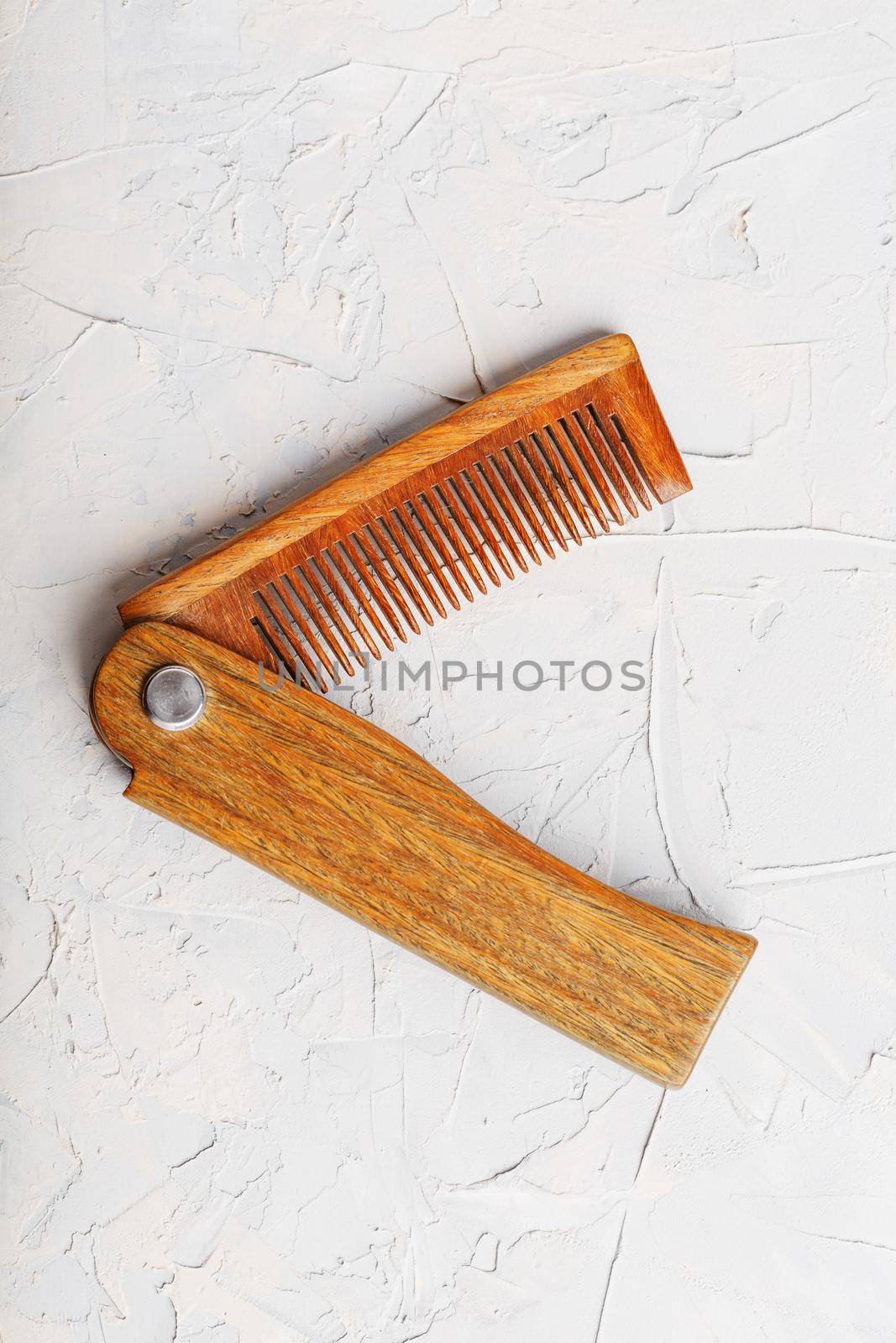 Wooden Sandalwood comb folding on a white textured background. by AlexGrec