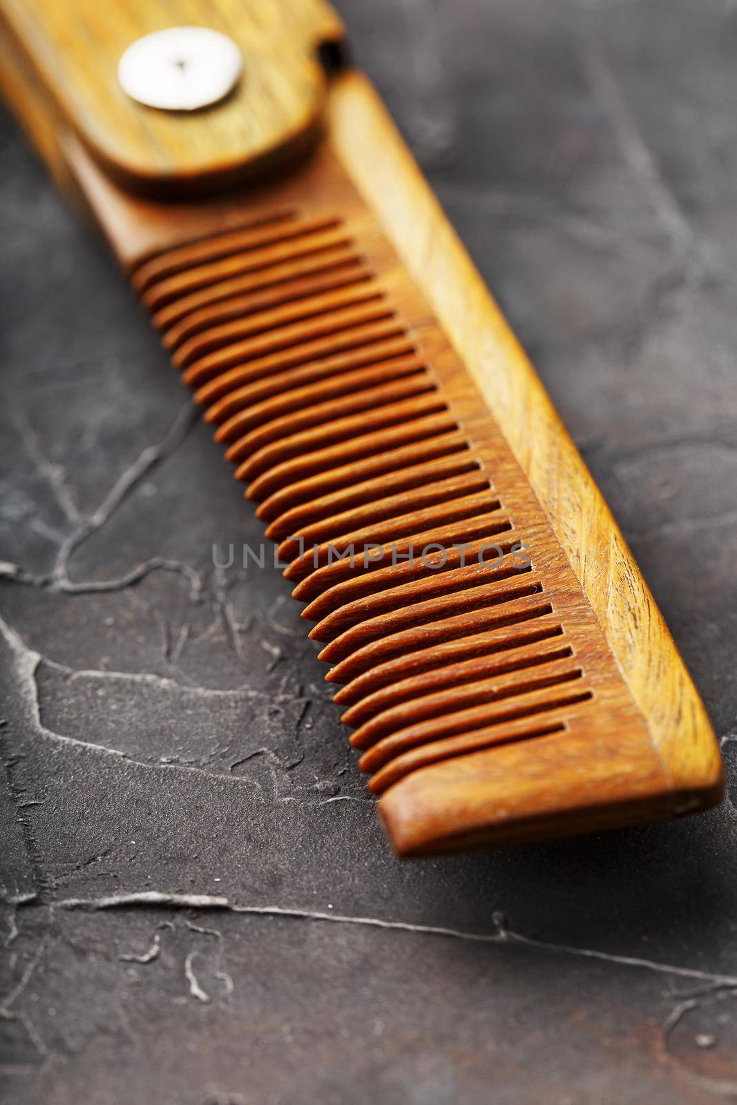 Wooden sandalwood comb on a black textured background. Hair care.