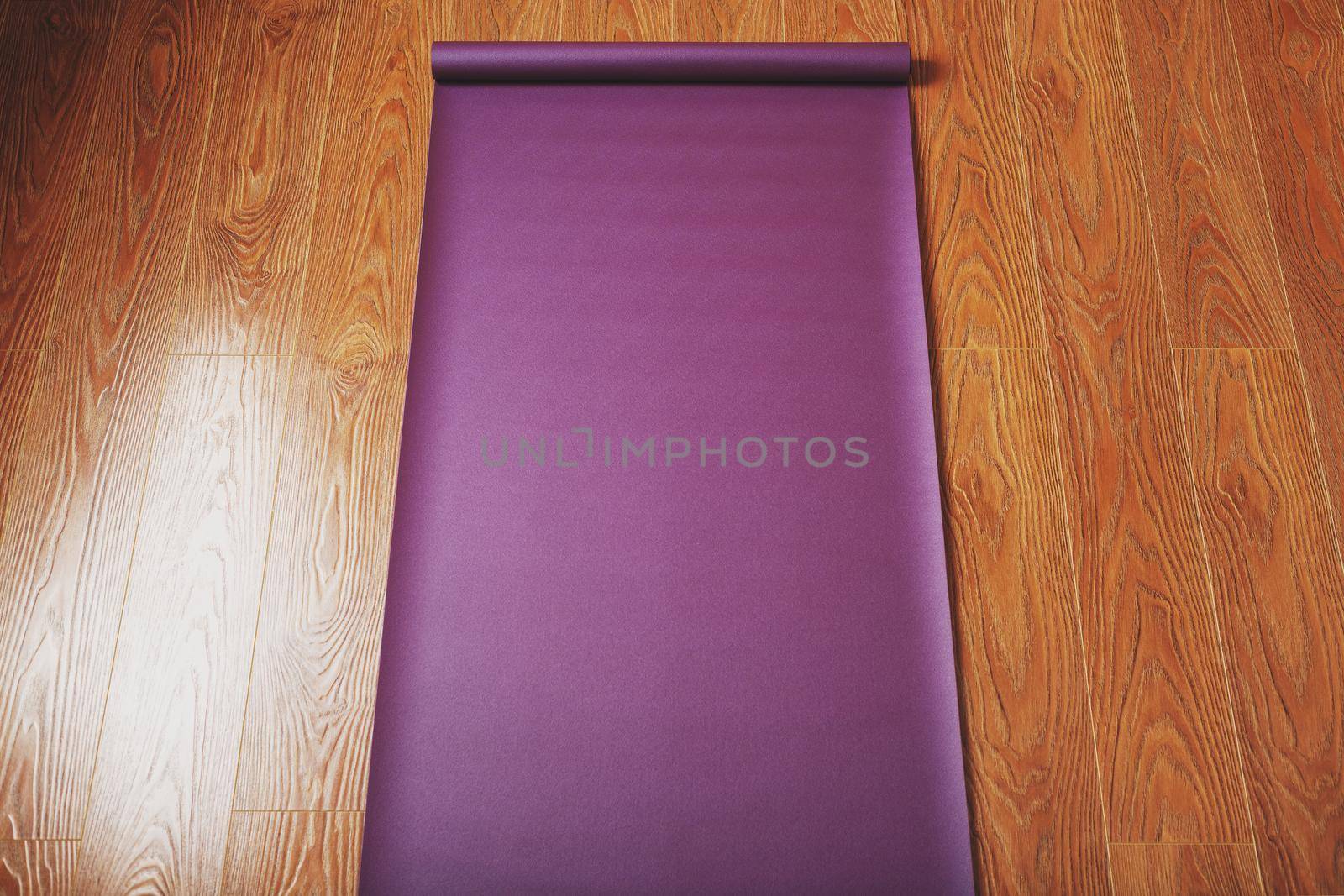 Purple yoga and fitness mat on wooden floor.