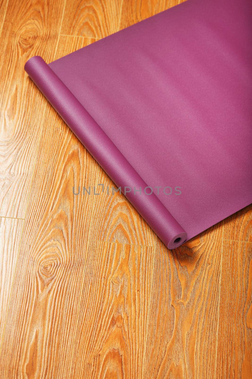 A lilac yoga mat is twisted on the wooden floor. by AlexGrec