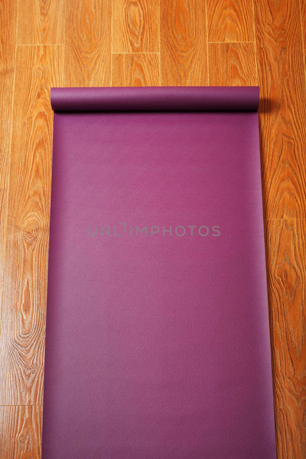 A lilac-colored yoga mat is spread out on the wooden floor with a Ganapati figurine. Top view
