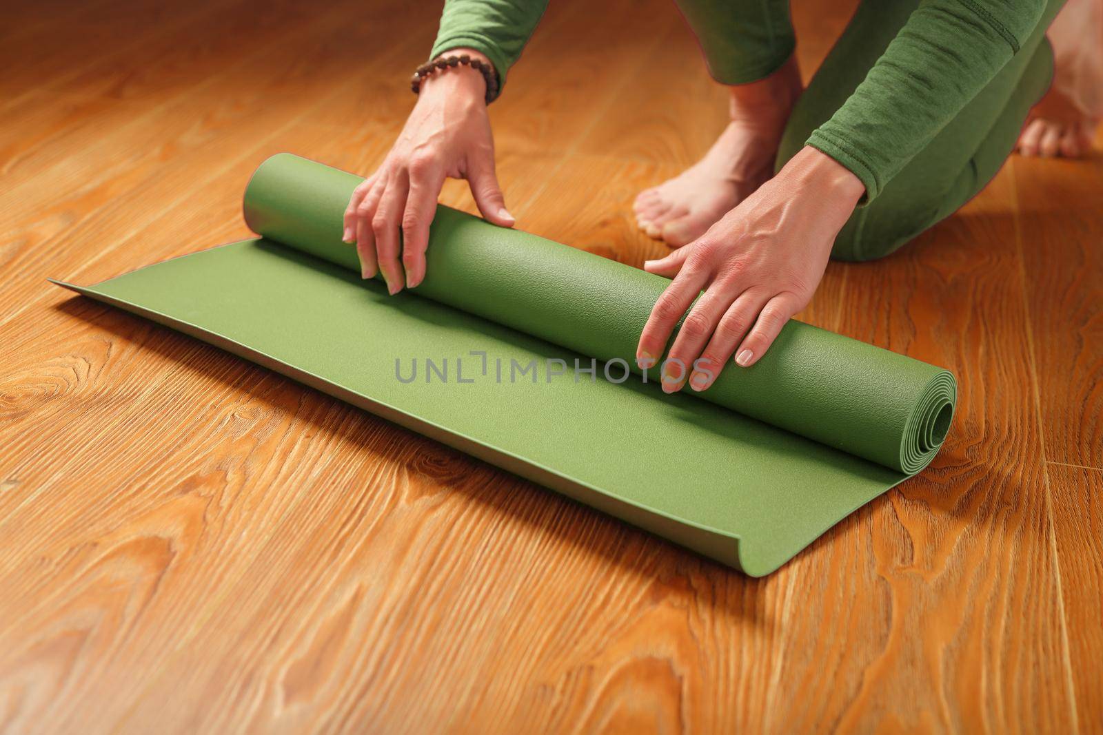 A woman collects a green mat after a yoga class by AlexGrec