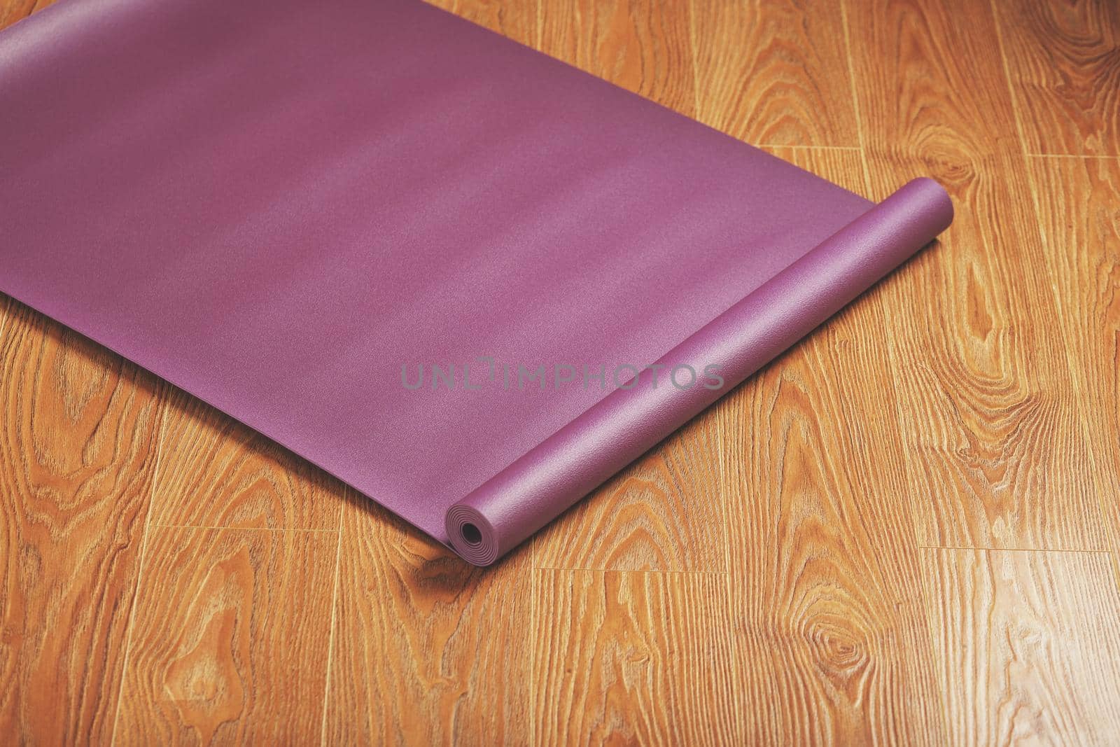 Purple yoga and fitness mat on wooden floor by AlexGrec
