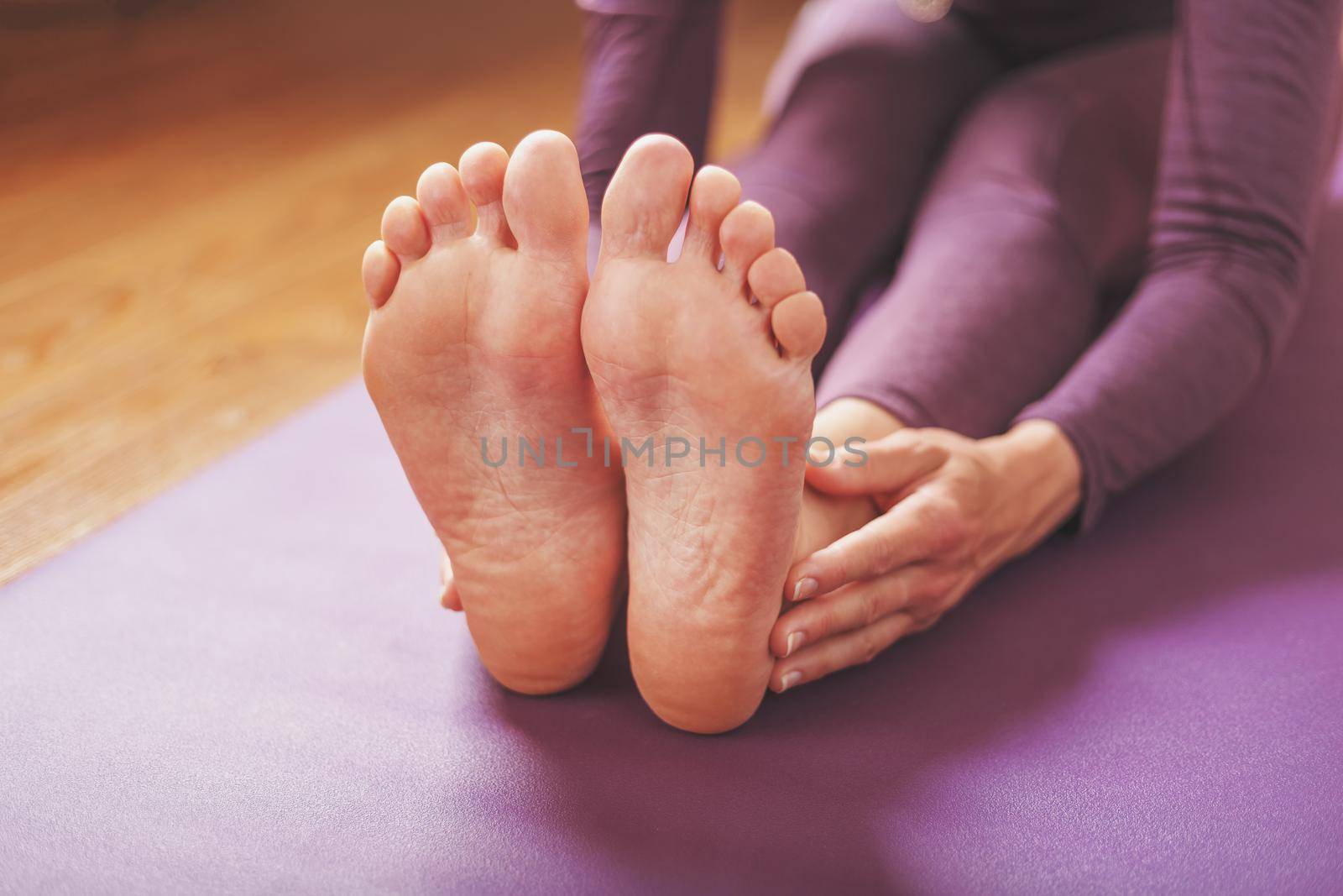 A girl does yoga asanas on a lilac rug in the living room.