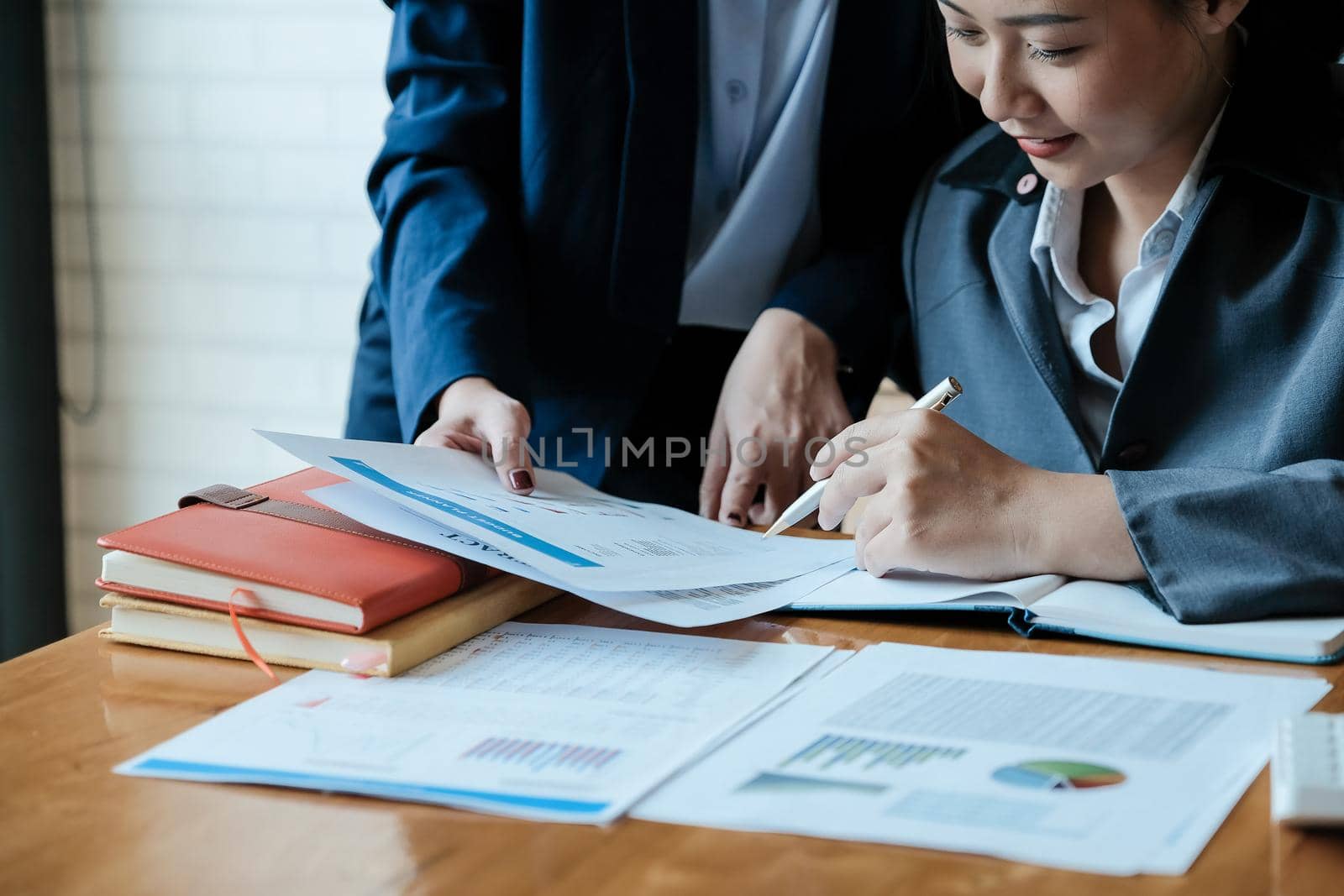 Close up of business people analyzing data from financial documents while working in the office by nateemee