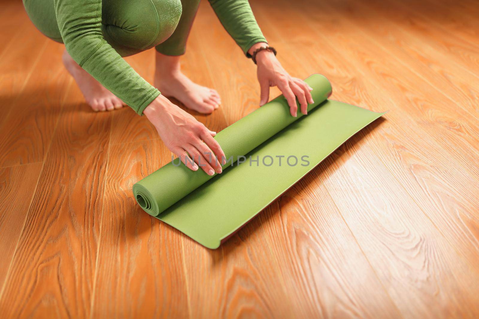 A woman collects a green mat after a yoga class.