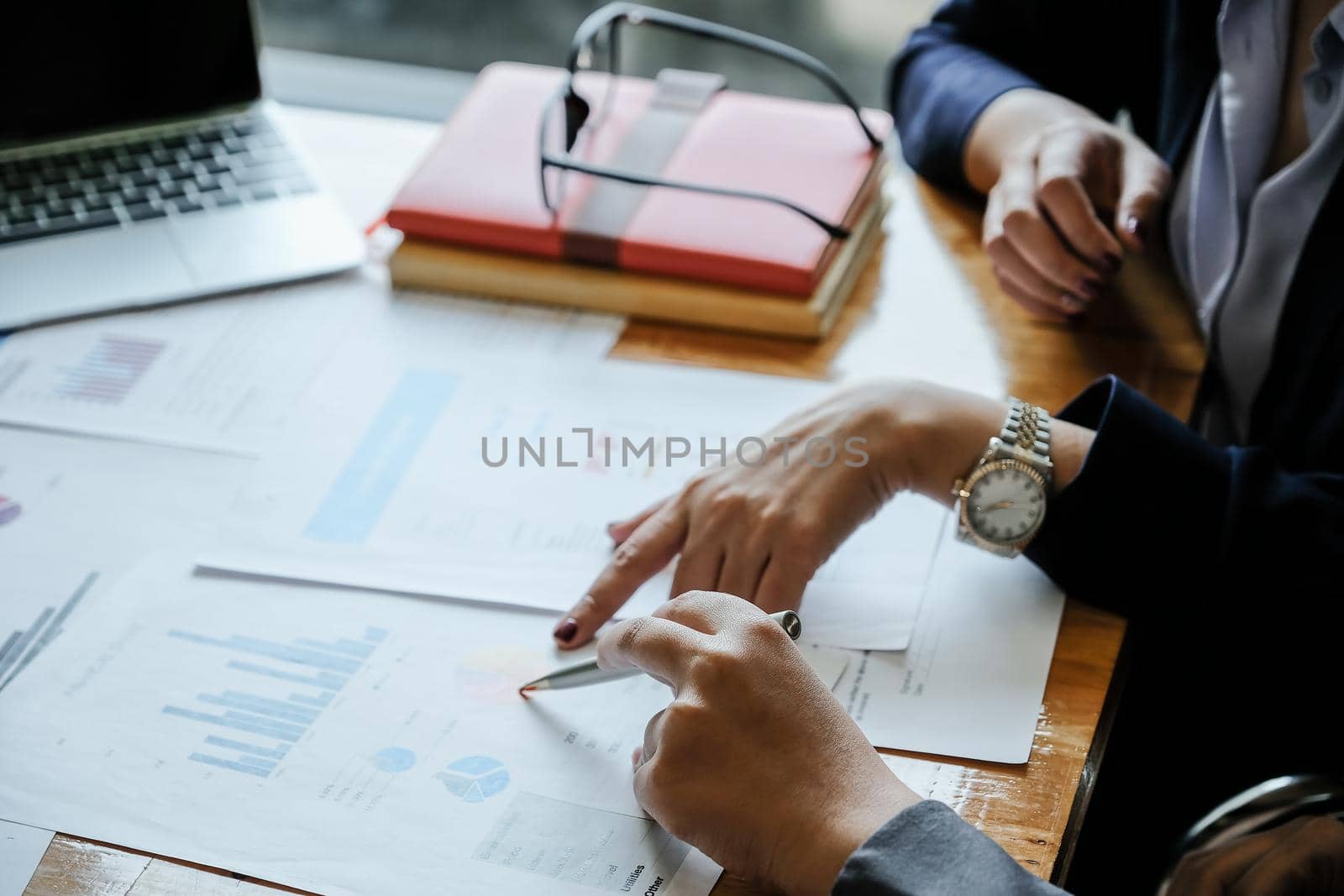 Close up of business people analyzing data from financial documents while working in the office.