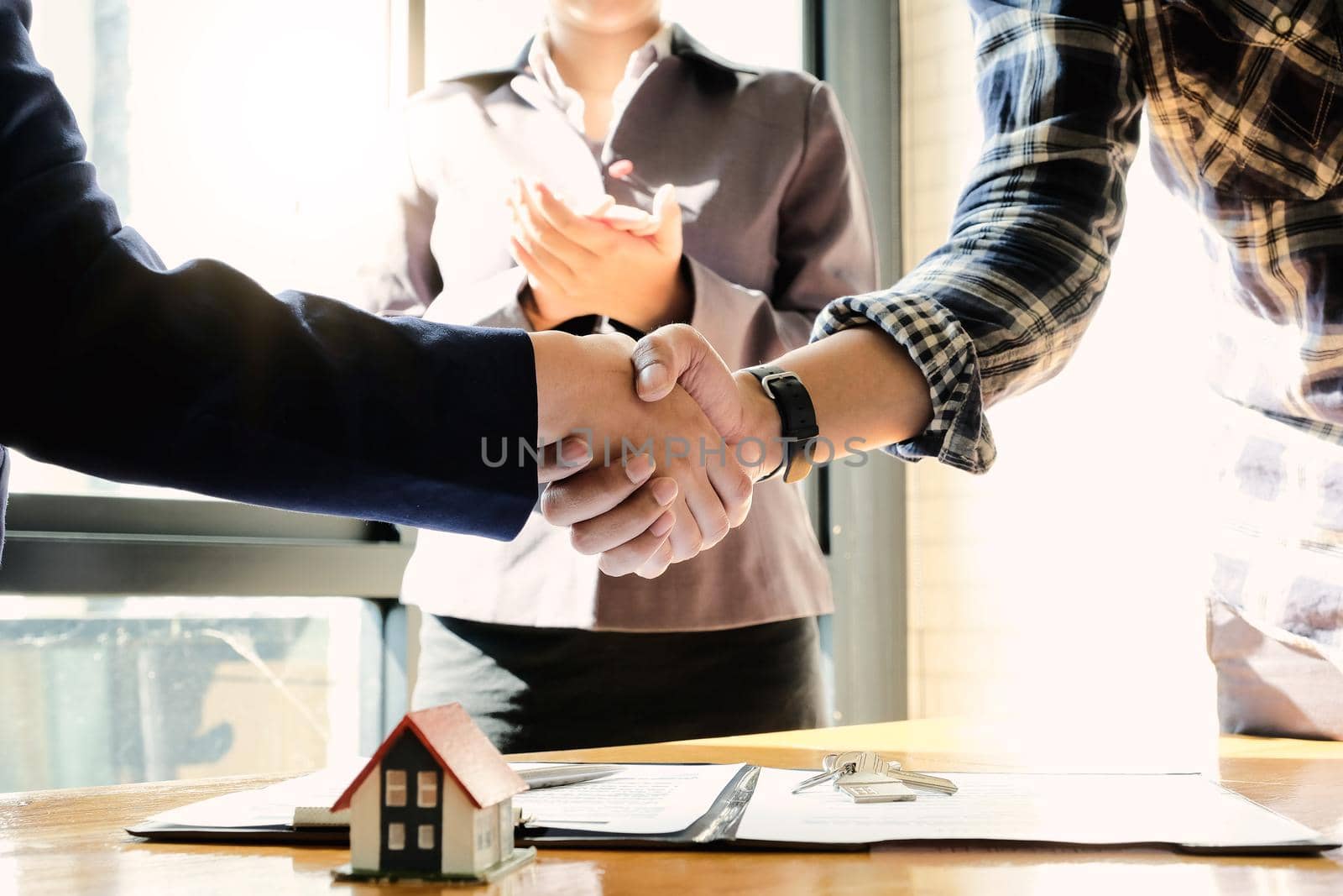 Real estate agent and customers shaking hands together celebrating finished contract after about home insurance by nateemee