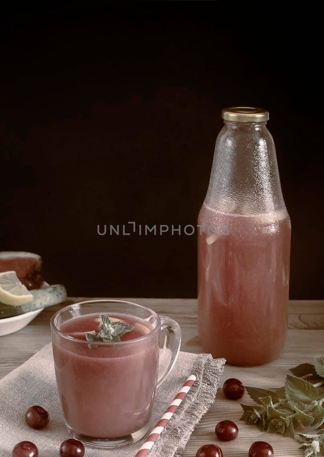 Fresh watermelon juice with cherries and lemon in a glass. Slices of watermelon and cherry berries on the table. Front view. Copy space. The concept of natural nutrition.
