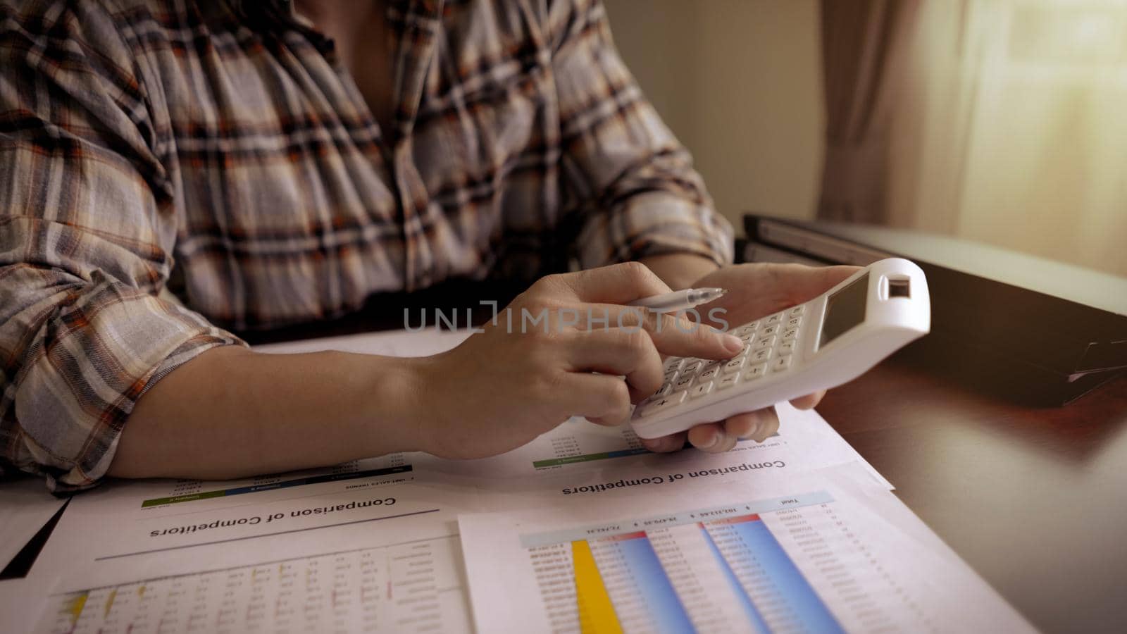 entrepreneur or Businessman using a calculator with a pen in her hand and calculate financial expense, tax, accounting, statistics and analytic research.