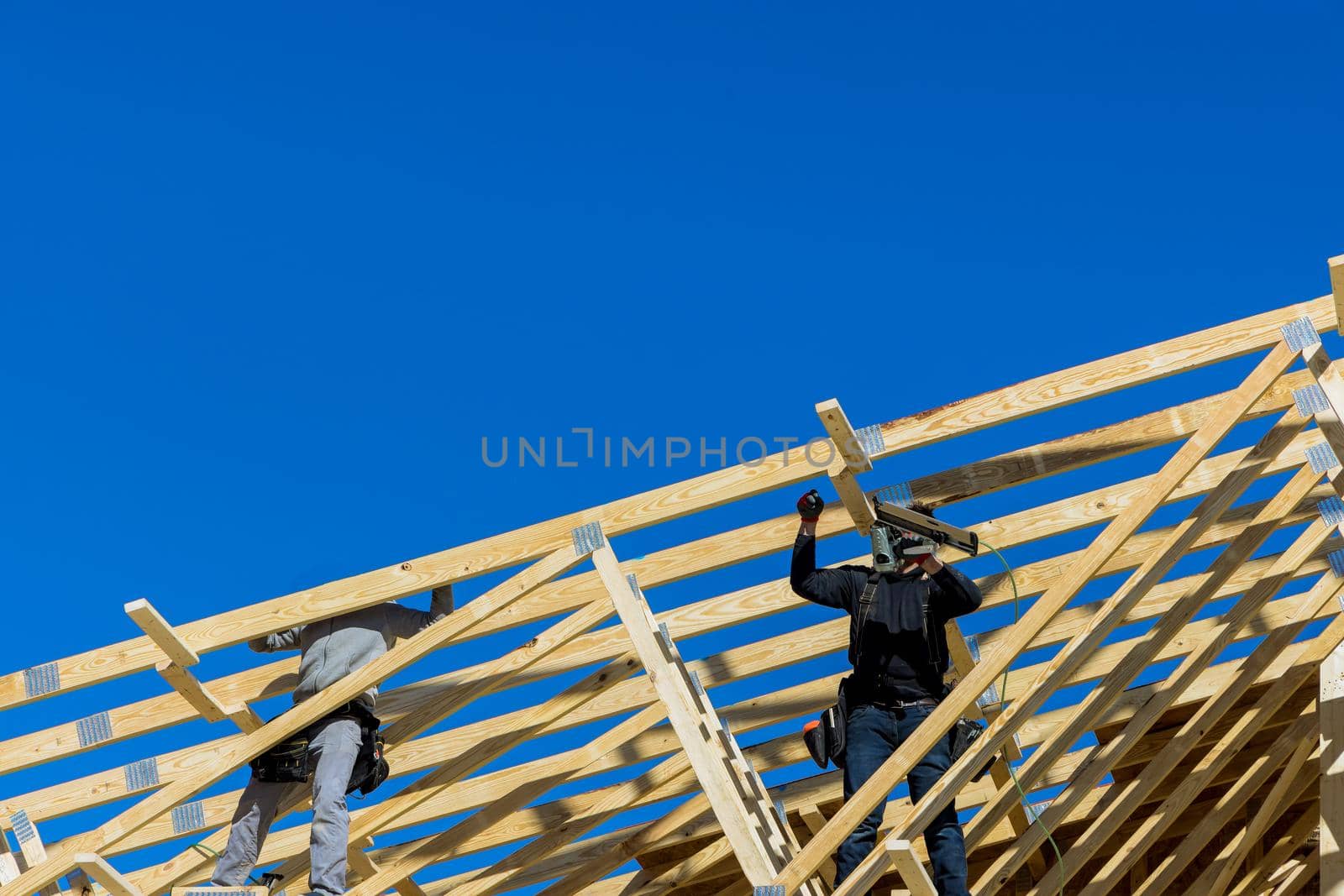 Construction building contractor working on the roof truss wood workers nailing wood beams