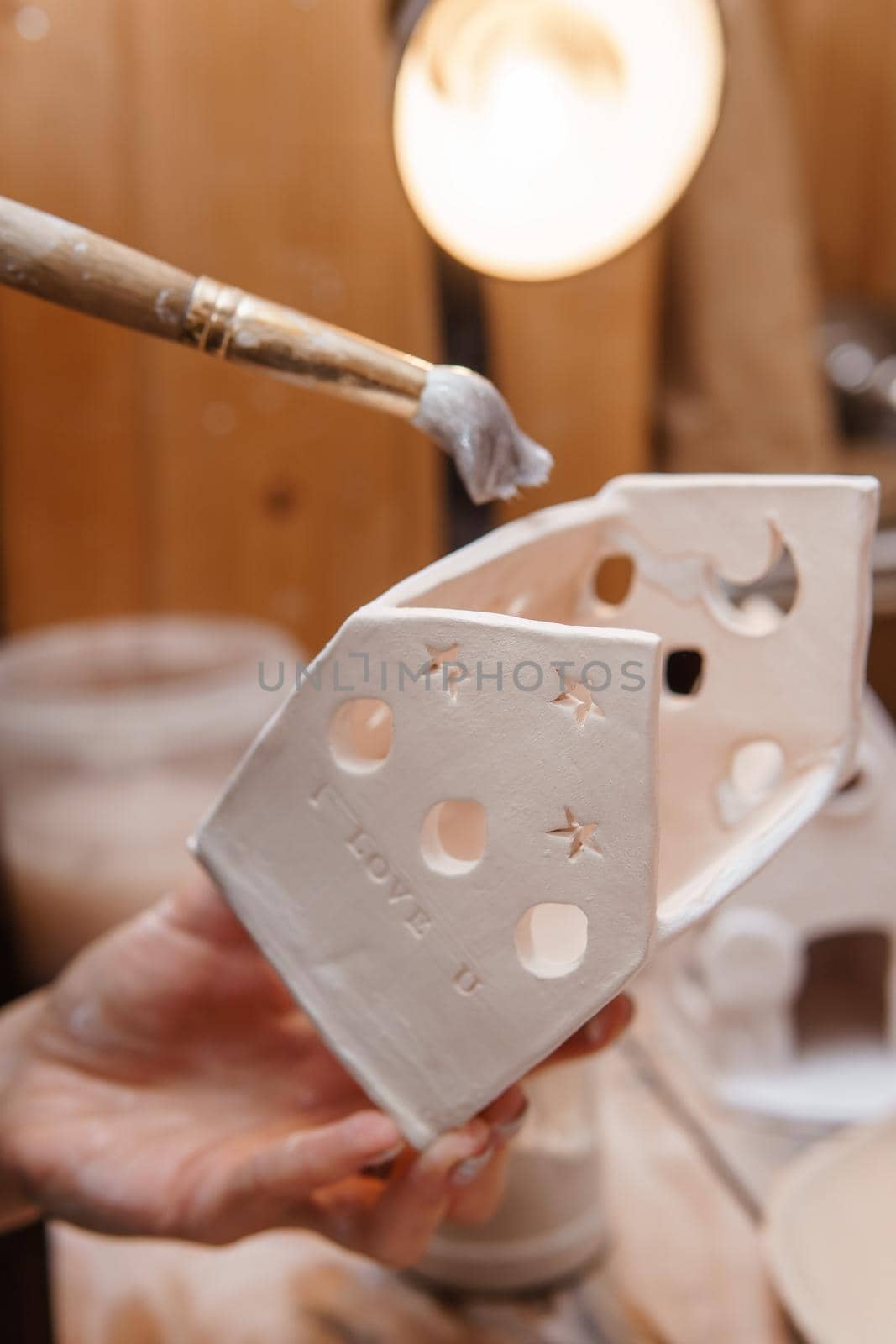 A master ceramist holds a clay product in his hands. Making a ceramic candle holder from clay. The process of coating the candlestick with glaze. Close-up.