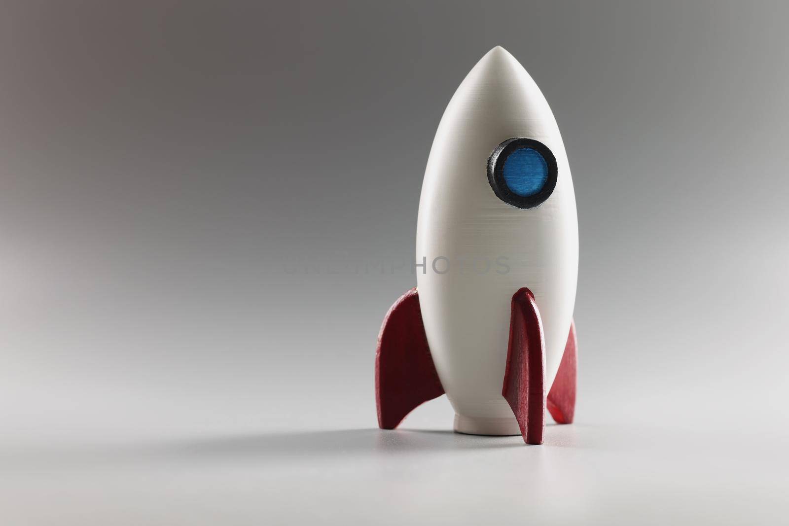 Close-up of miniature rocket toy stand on surface, rocketship as symbol for business project and startup. Success, development, growth concept. Copy space