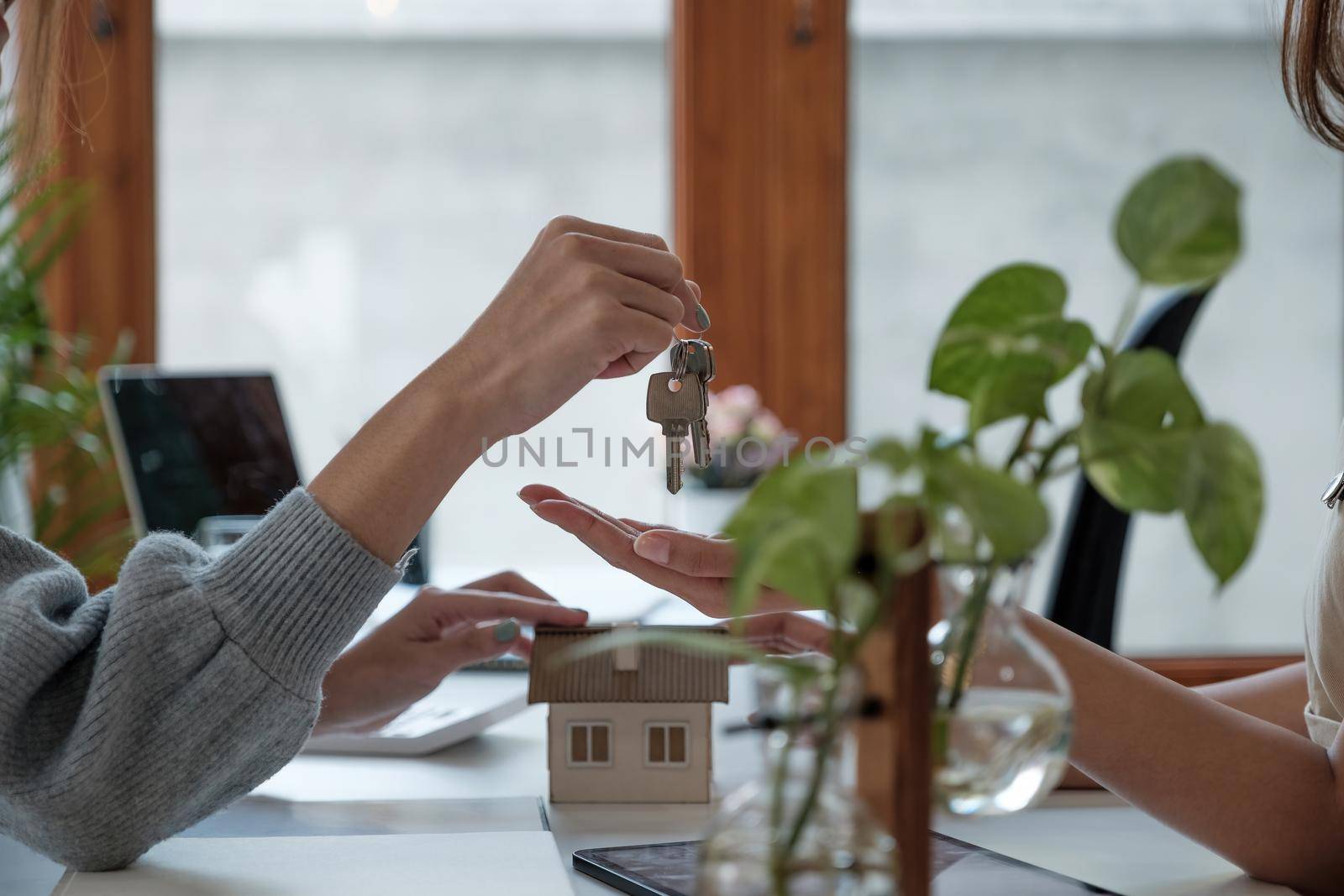 real estate agent holding house key to his client after signing contract agreement in office,concept for real estate, moving home or renting property.