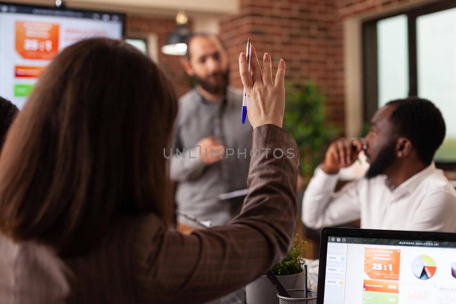 Businesswoman having rising hand having marketing question during business meeting working at company presentation in startup office. Diverse businesspeople discussing strategy analyzing graphs