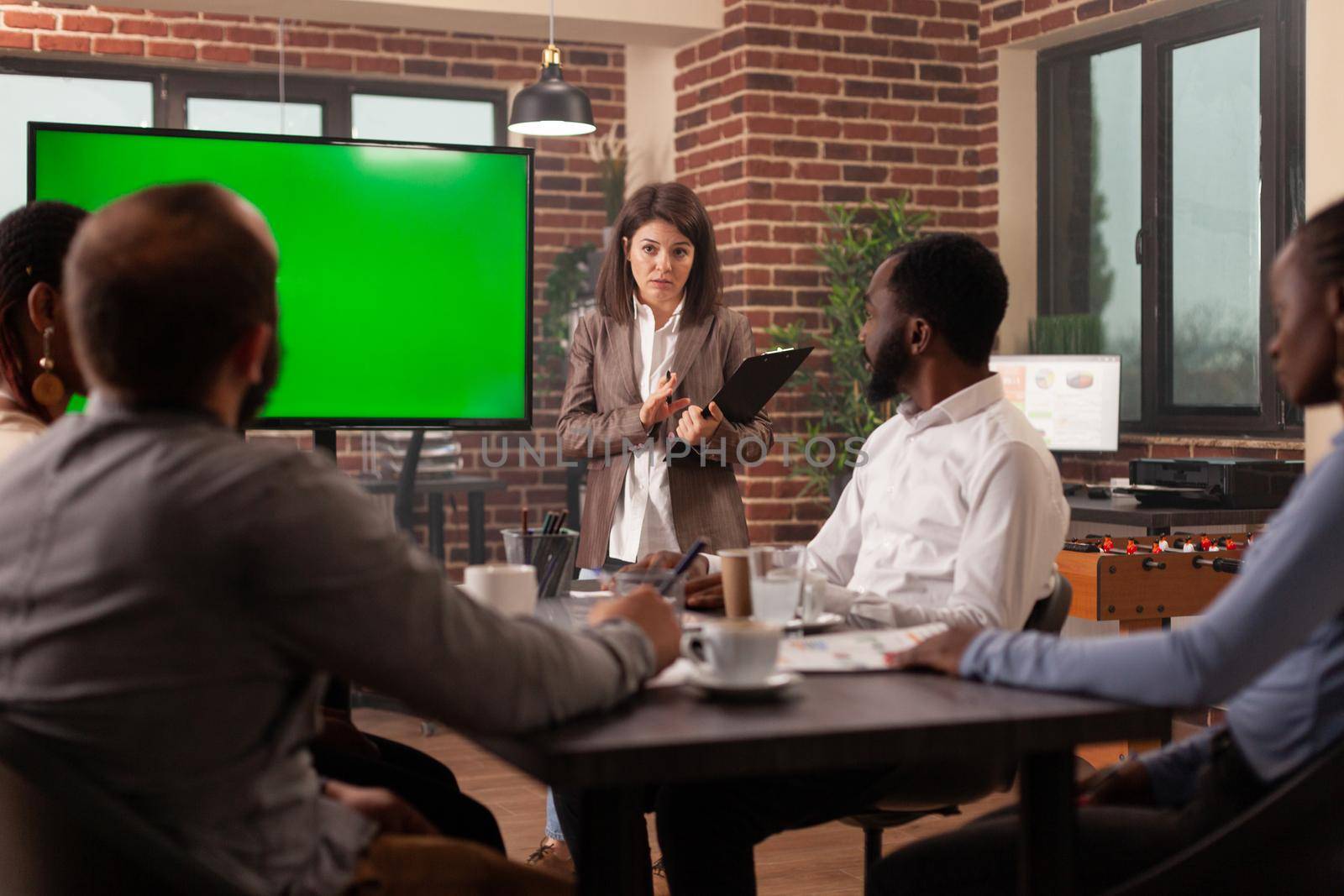 Executive manager woman planning company presentation explaining management strategy to businessteam working in startup office. Mock up green screen chroma key monitor isolated display