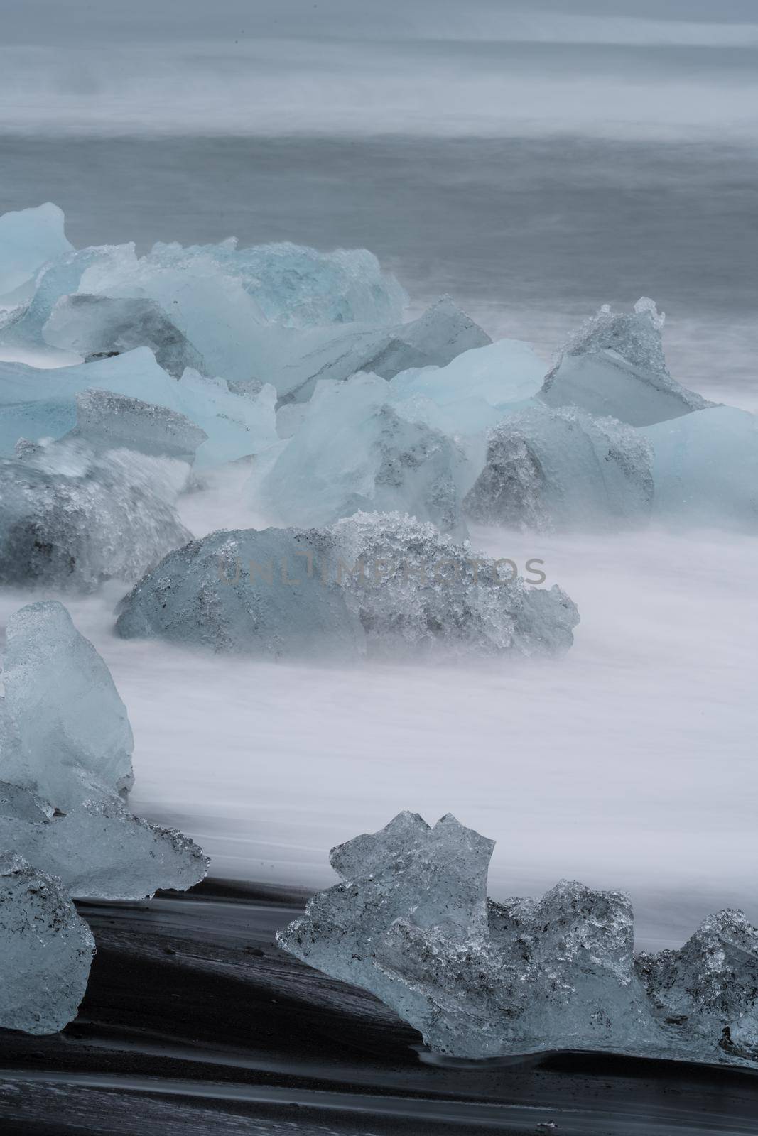 Icebergs over Jokulsarlon black diamong beach, vertical composition, long exposure
