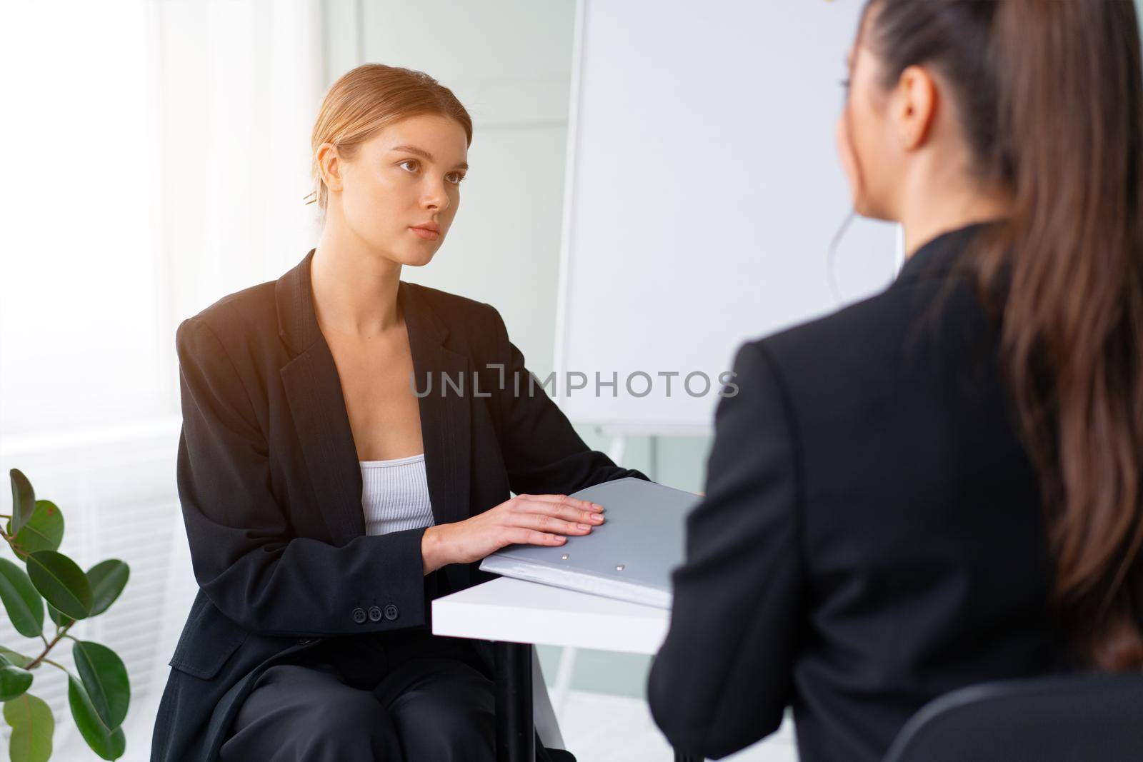 Job interview. Business, career and placement concept. Young blonde woman holding resume, while sitting in front of candidate during corporate meeting. Boss discuss ideas with business partner