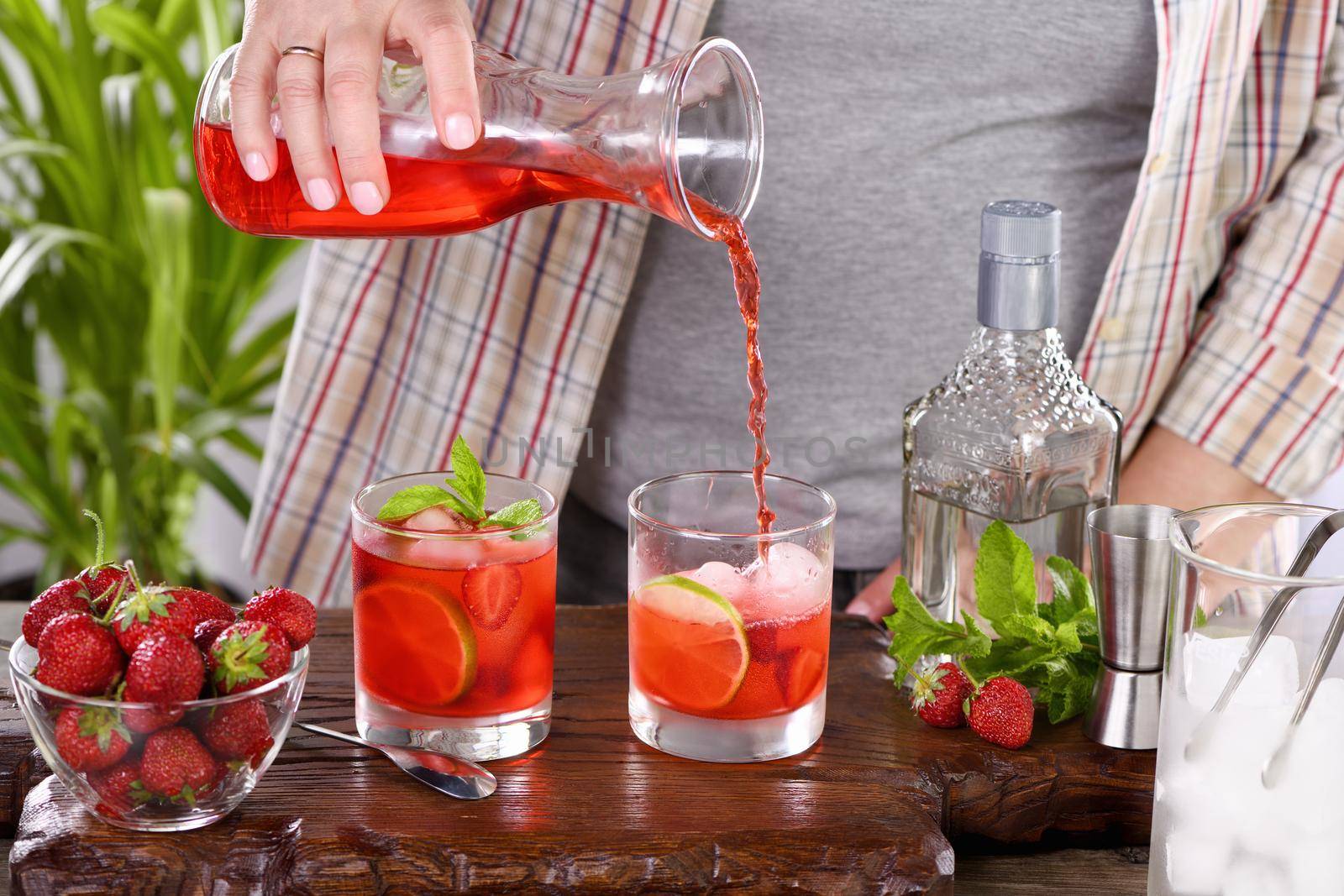 The bartender prepares a refreshing strawberry mojito cocktail with ice, fresh mint and lime. Great idea for a picnic or summer party. It may contain alcohol or be a mocktail.